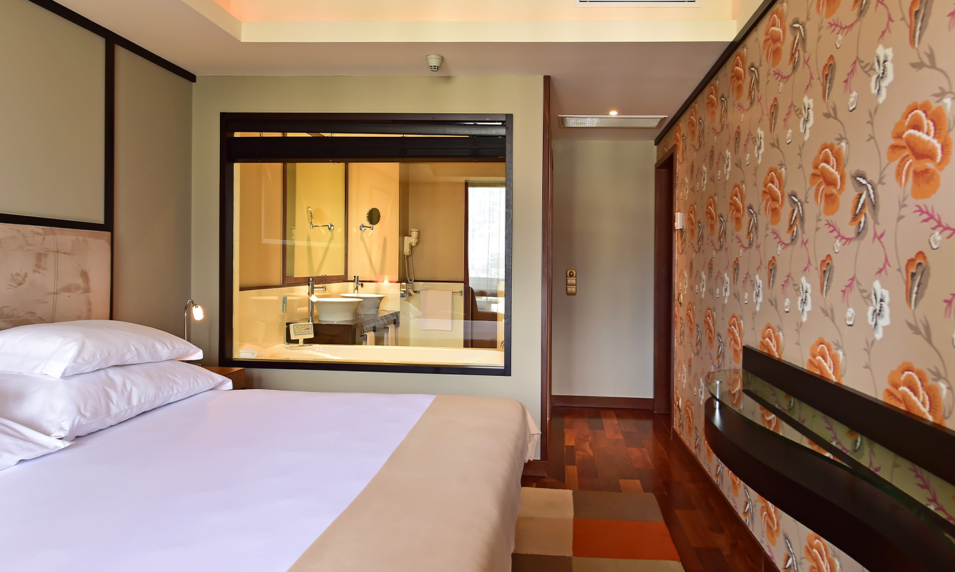 Die Präsidentensuite im Pestana Casino Park hat ein Doppelbett mit Glas für das Badezimmer und Tapete zur Dekoration