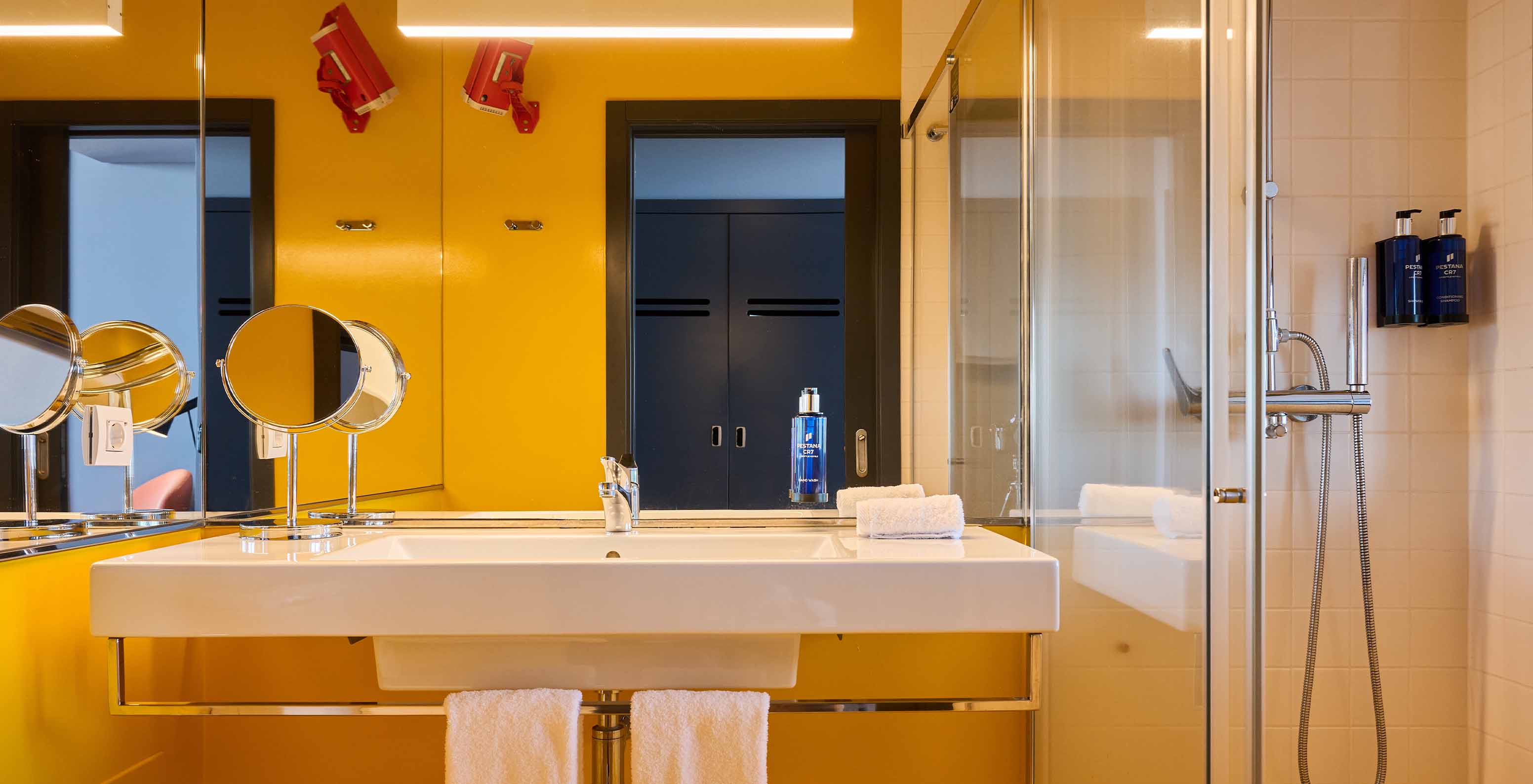 Das CR Superior Zimmer im Pestana CR7 Funchal hat ein modernes Bad in Gelbtönen mit Dusche