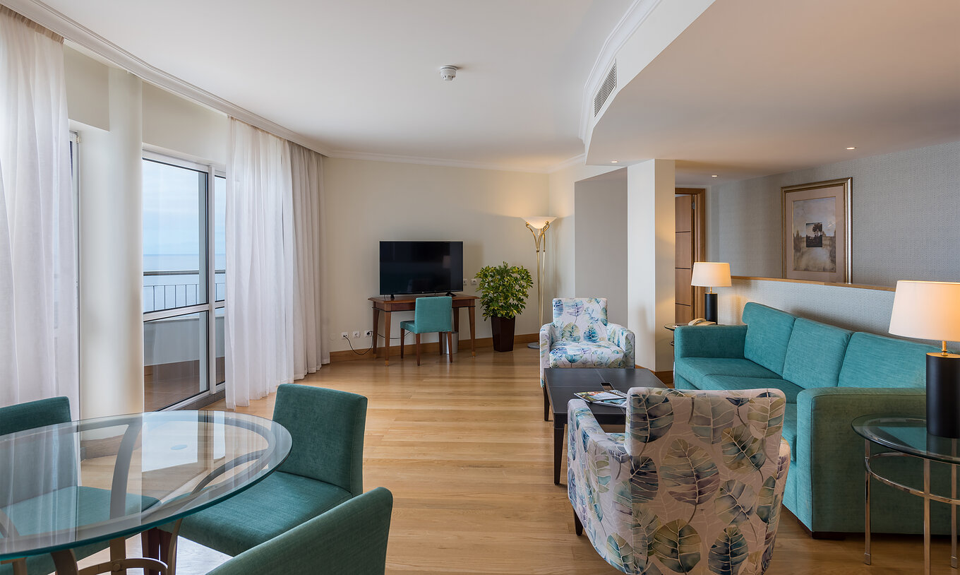 Die Master Suite mit Meerblick im Pestana Grand hat Wohnzimmer, Sofa und Tisch sowie Fernseher