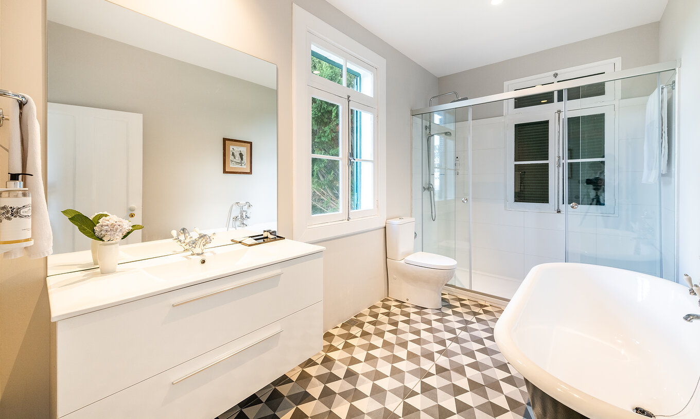 Die Manor House - 1 hat ein Bad mit Badewanne und Dusche, Waschbecken mit großem Spiegel und Fenster 