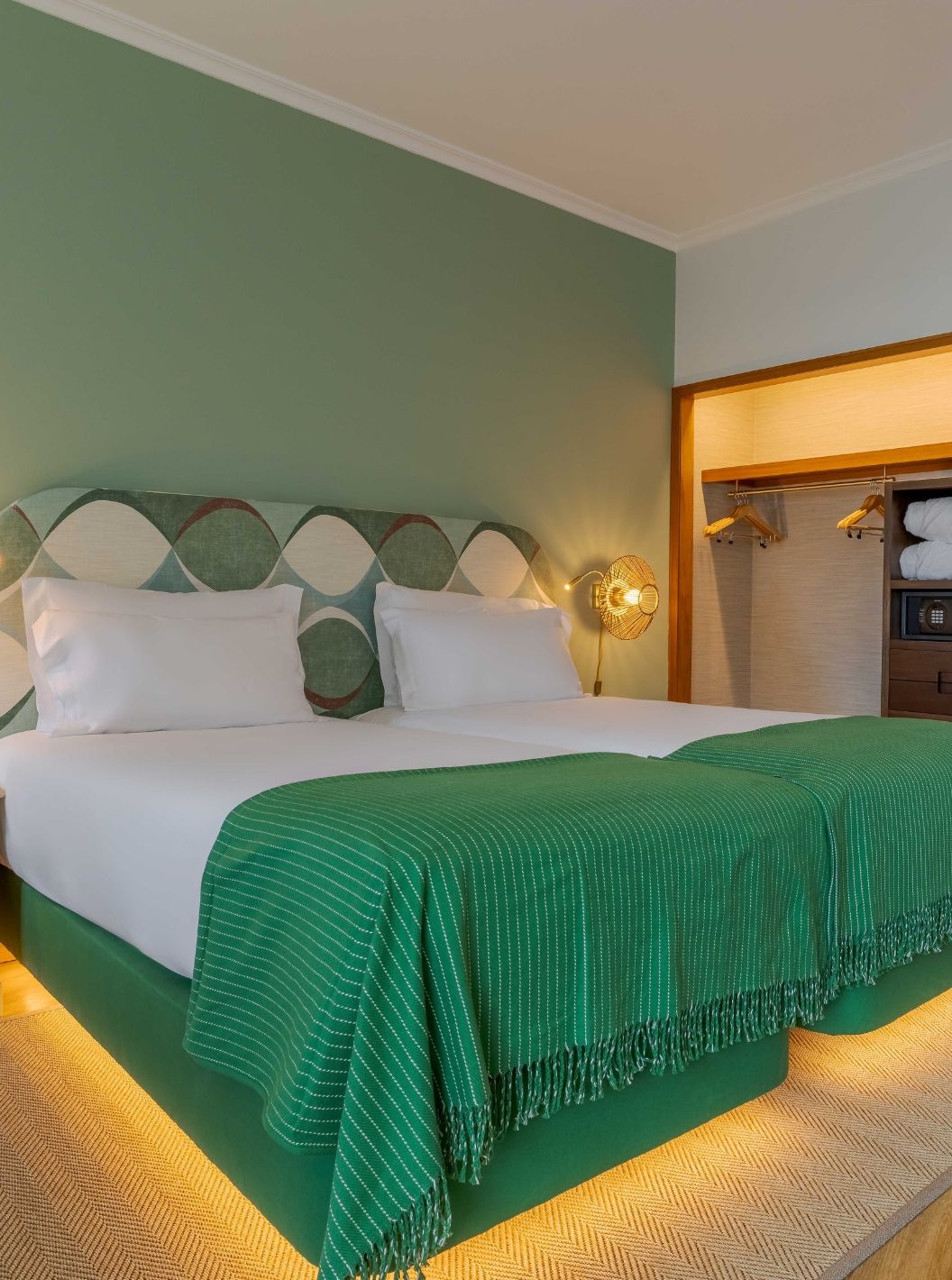 Das Superior seitlicher Meerblick im Pestana Vila Lido Madeira verfügt über ein Doppelbett mit grünem Kopfteil und Kleiderschrank.