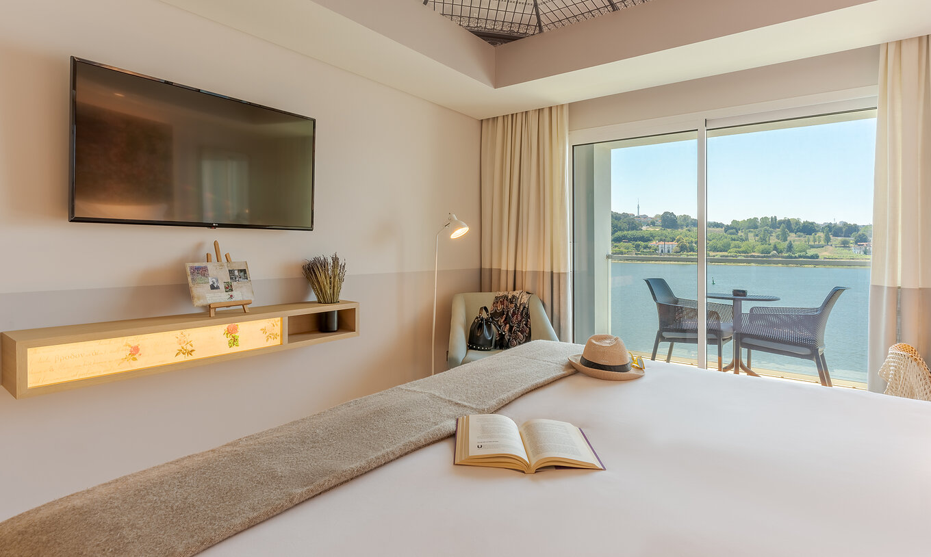Das Deluxe River View Zimmer im Pestana Douro Riverside hat ein Doppelbett, Fernseher und Sessel