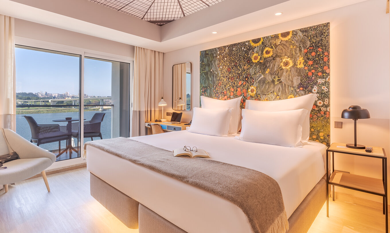 Das Grand River View Zimmer im Pestana Douro Riverside hat ein Doppelbett, Nachttisch und Balkon