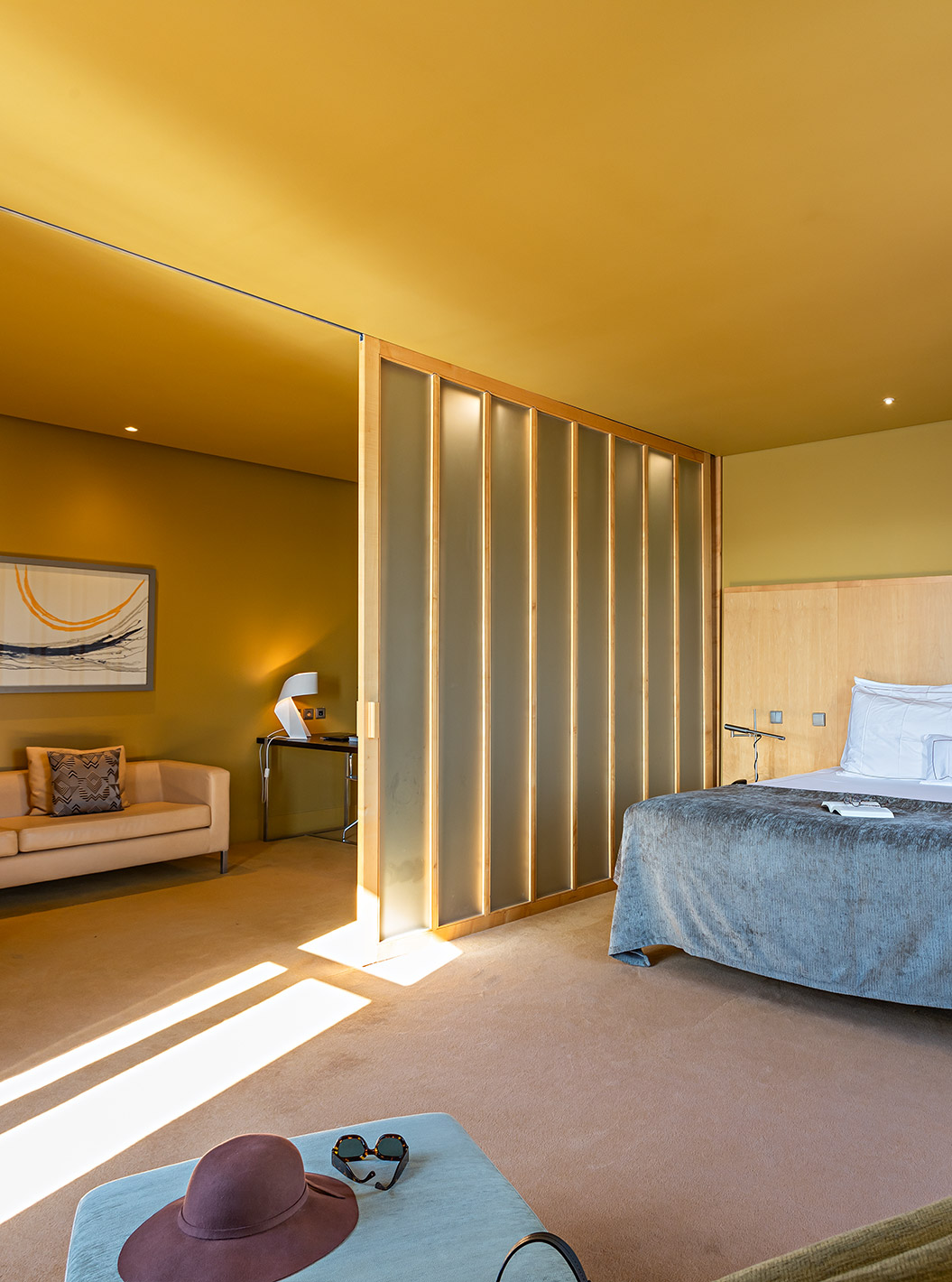 Die Standard Suite verfügt über ein großes Doppelbett mit grauer Decke und einem sofa