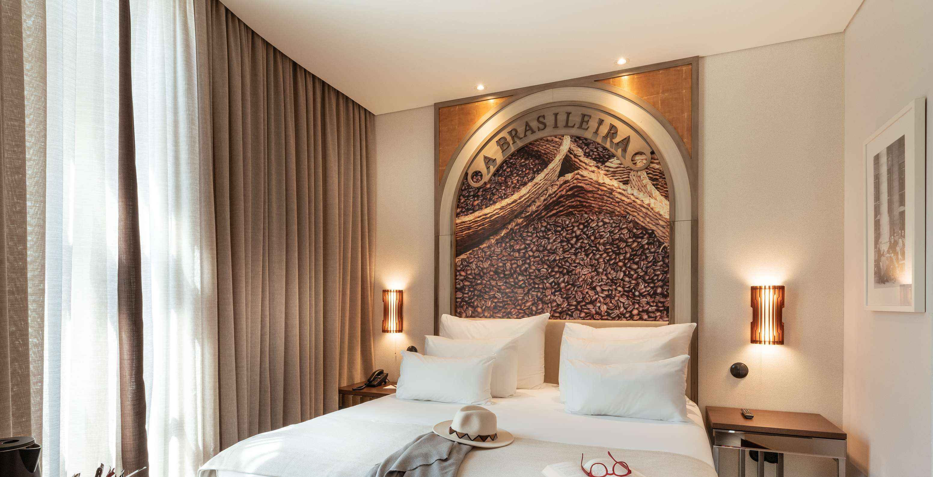 Classic Blend Zimmer im Pestana A Brasileira Porto mit Doppelbett, Kaffeemotiv und hohen Vorhängen bei Tageslicht