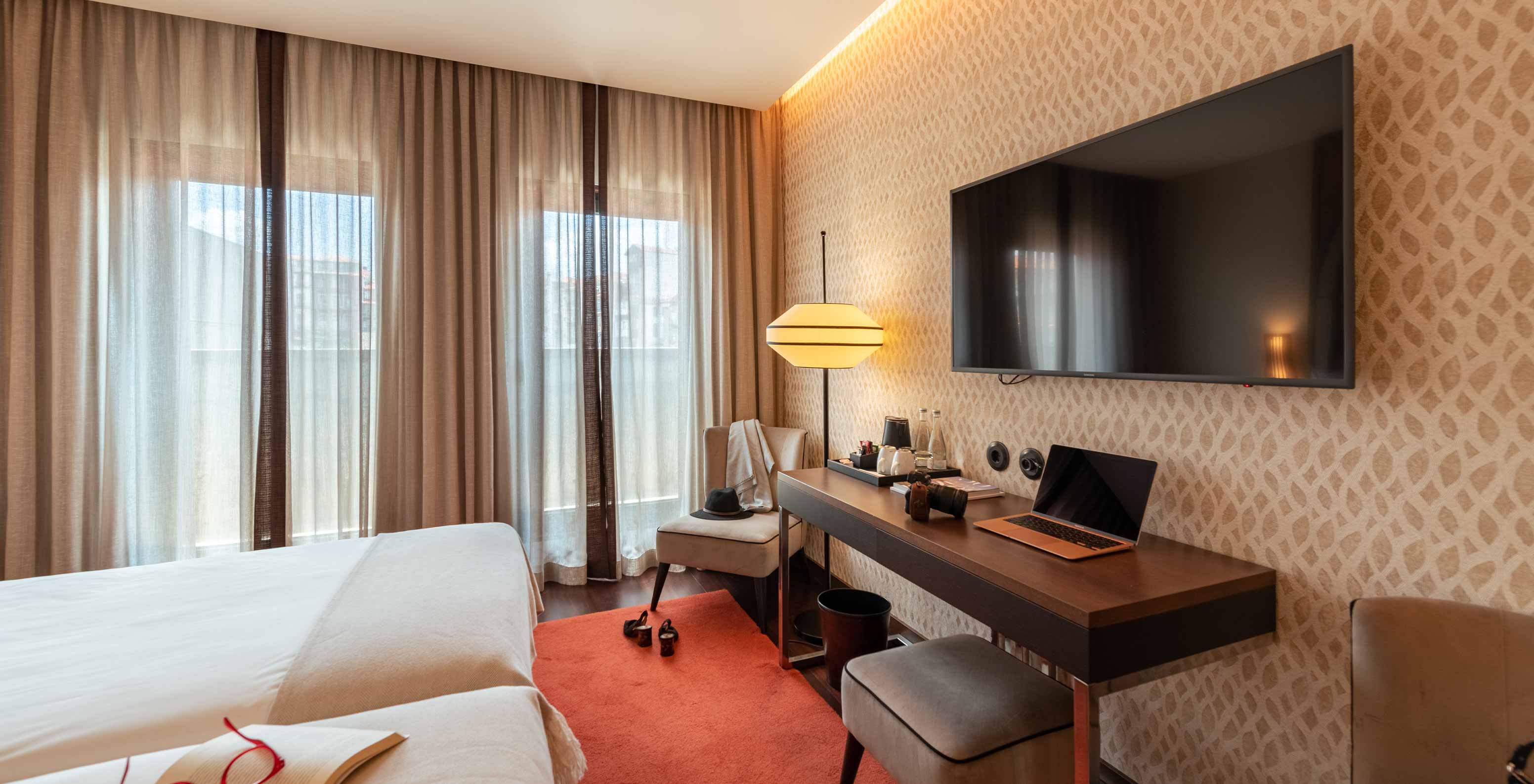 Klassisches Zimmer mit französischem Balkon im Pestana A Brasileira Porto mit Bett, Schreibtisch und Fernseher