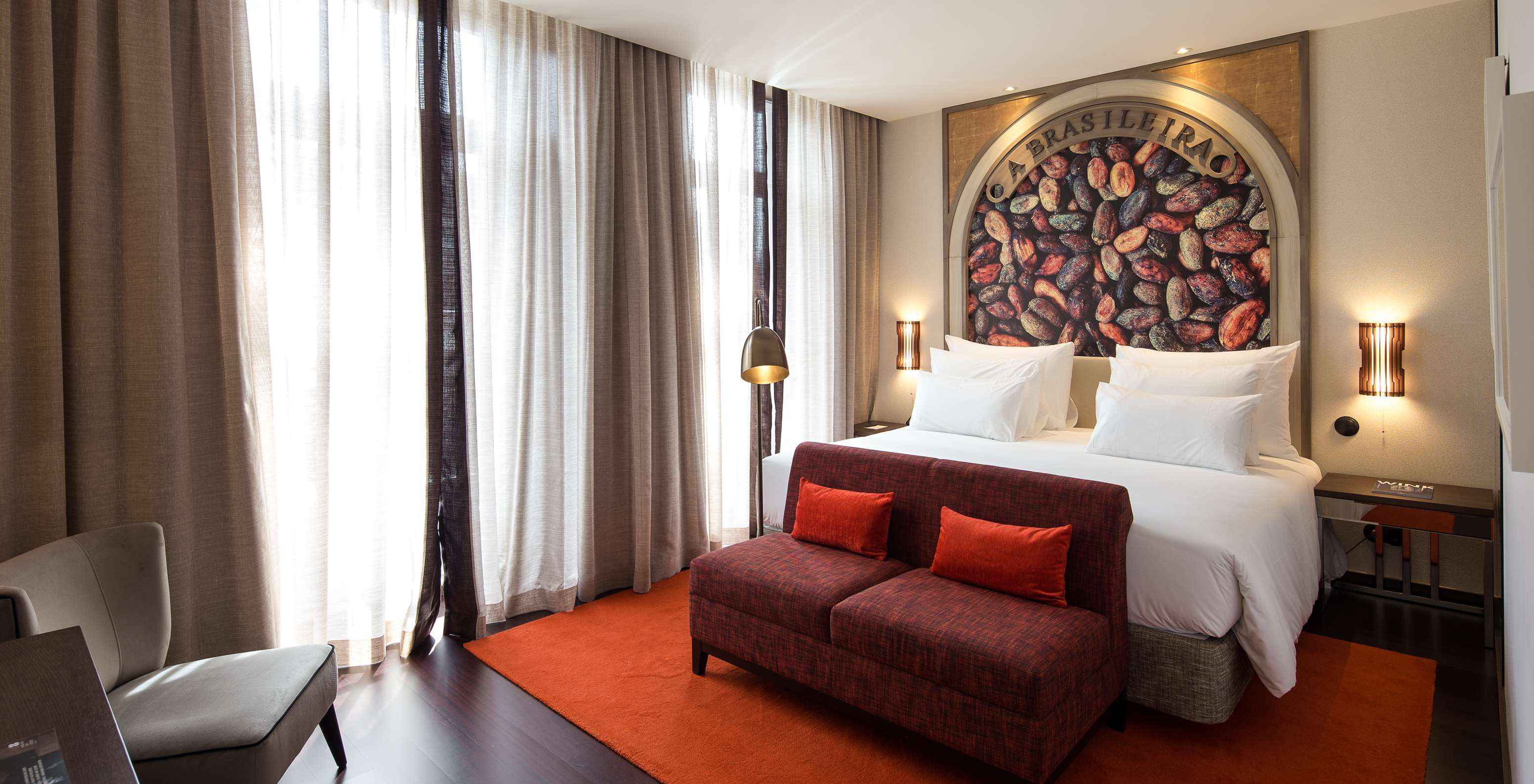 Premium Origin Zimmer mit französischem Balkon im Pestana A Brasileira Porto mit Bett und rotem Sofa