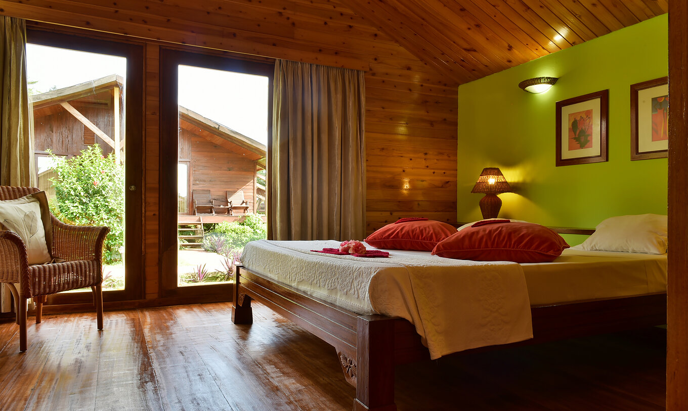Die Standard Suite im Pestana Equador hat Doppelbett, Stuhl und Fenster mit Gartenblick