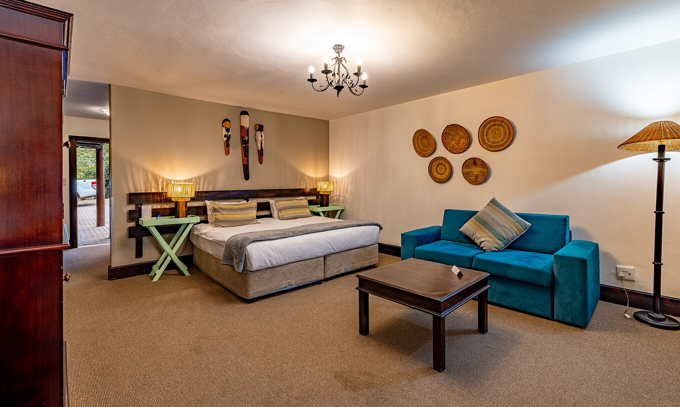 Das Premium Zimmer im Pestana Kruger Lodge hat Doppelbett, blauen Sofa und afrikanische Dekoration