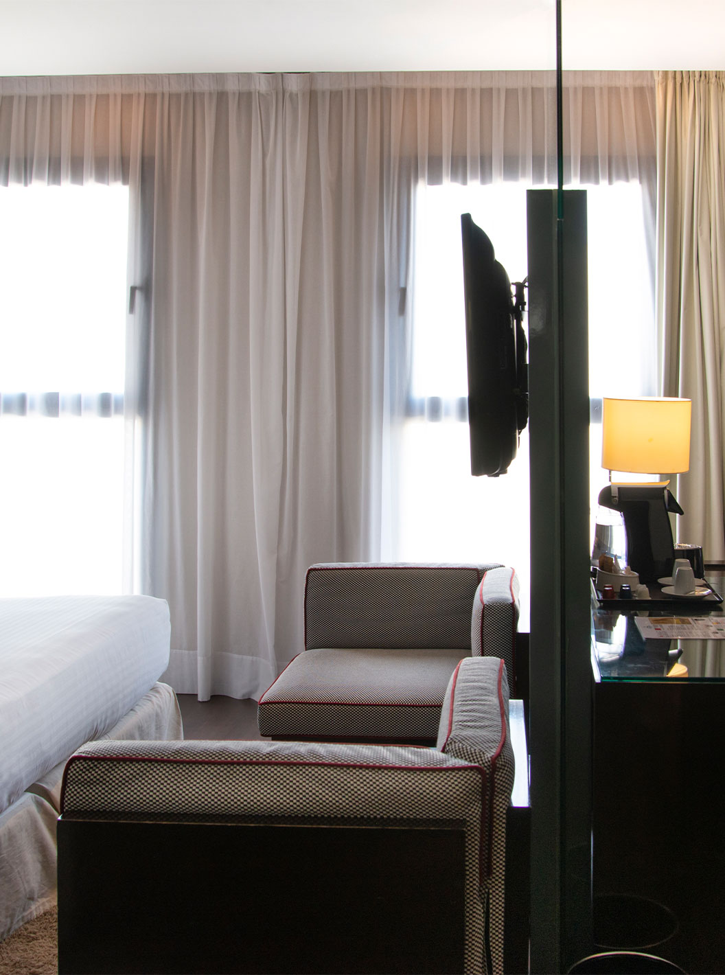 Das Deluxe King Zimmer im Pestana Arena Barcelona hat zwei kleine Sofas, einen Fernseher und einen Schreibtisch