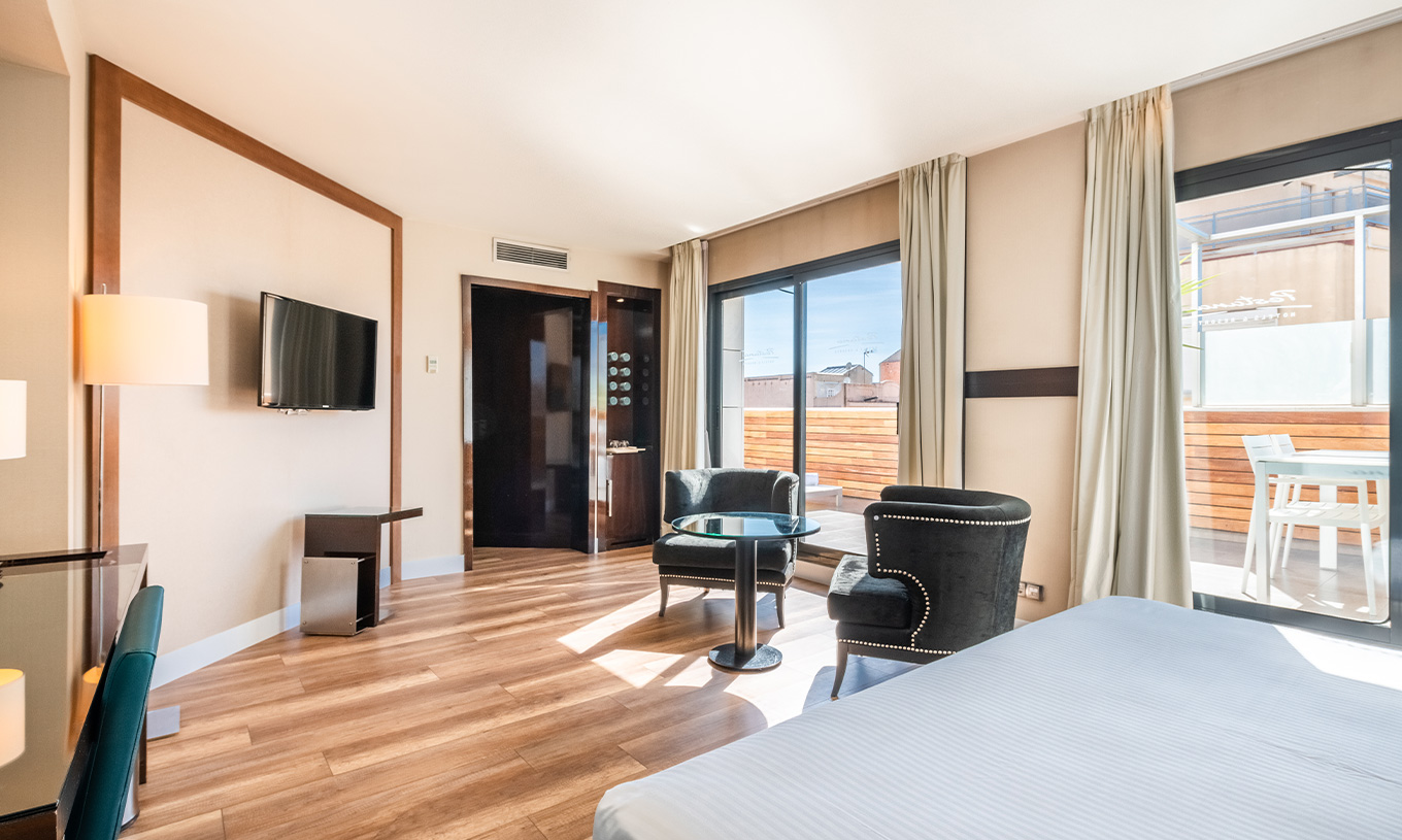 Die Junior Suite im Pestana Arena Barcelona hat einen Balkon mit Tisch und Stühlen und Blick auf die Stadt