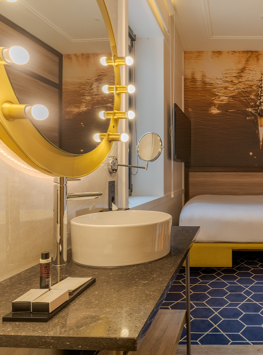 Cozy Zimmer im Pestana CR7 Gran Vía Madrid mit rundem Spiegel, Waschbecken und Blick auf das Bett im Hintergrund