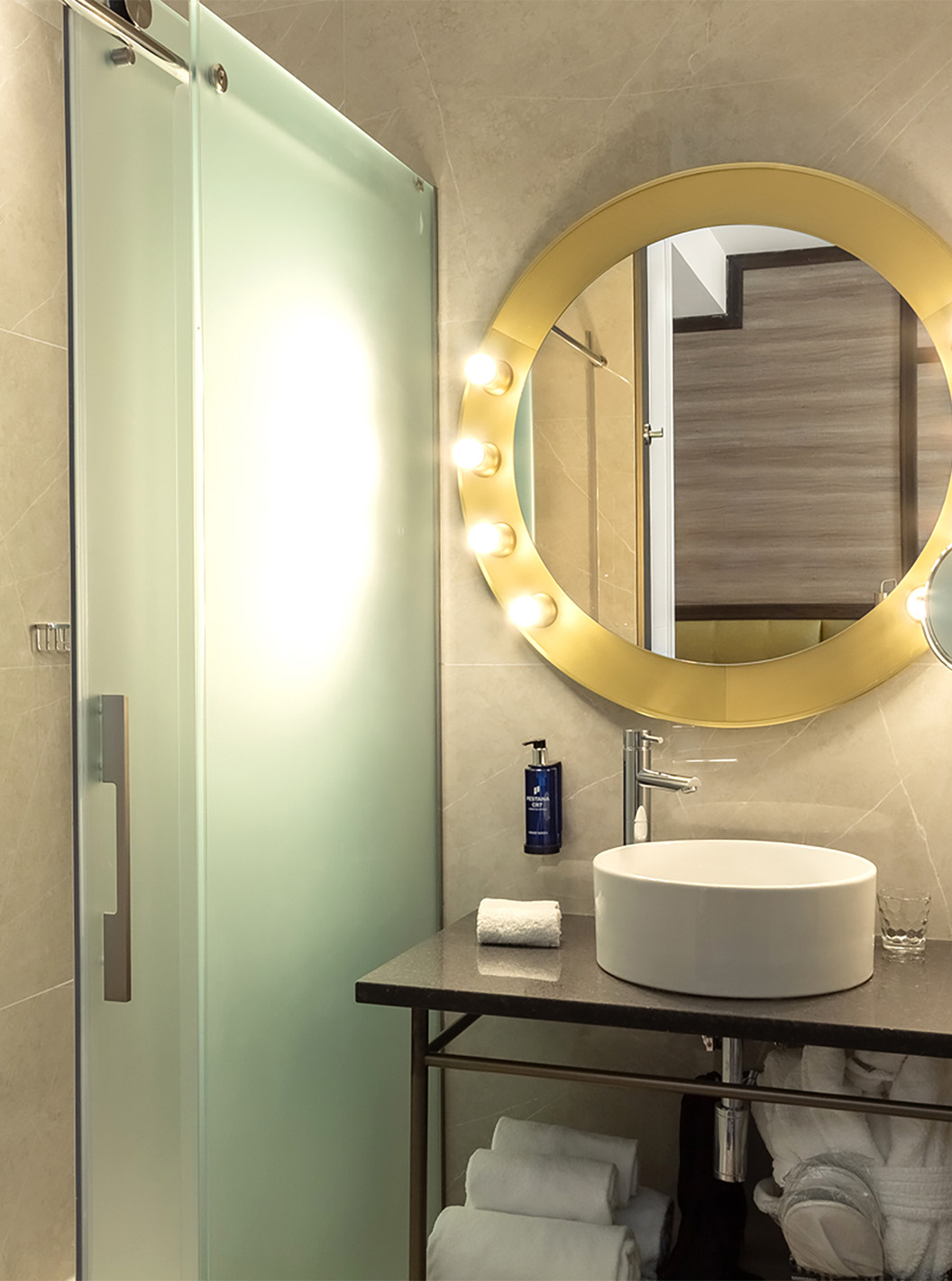 Das Deluxe Grand Zimmer im Pestana CR7 Gran Vía Madrid hat ein Badezimmer mit Spiegel, Waschbecken und Glastüren