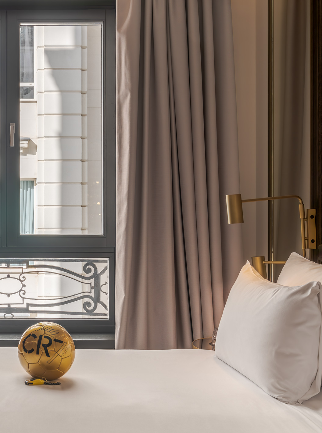 Premium Zimmer im Pestana CR7 Gran Vía Madrid mit Bett, goldfarbenem Fußball und Fenster mit Vorhängen