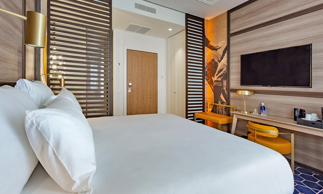 Das Premium Zimmer im Pestana CR7 Gran Vía Madrid hat ein Doppelbett, Schreibtisch mit Stuhl, Lampe und Fernseher