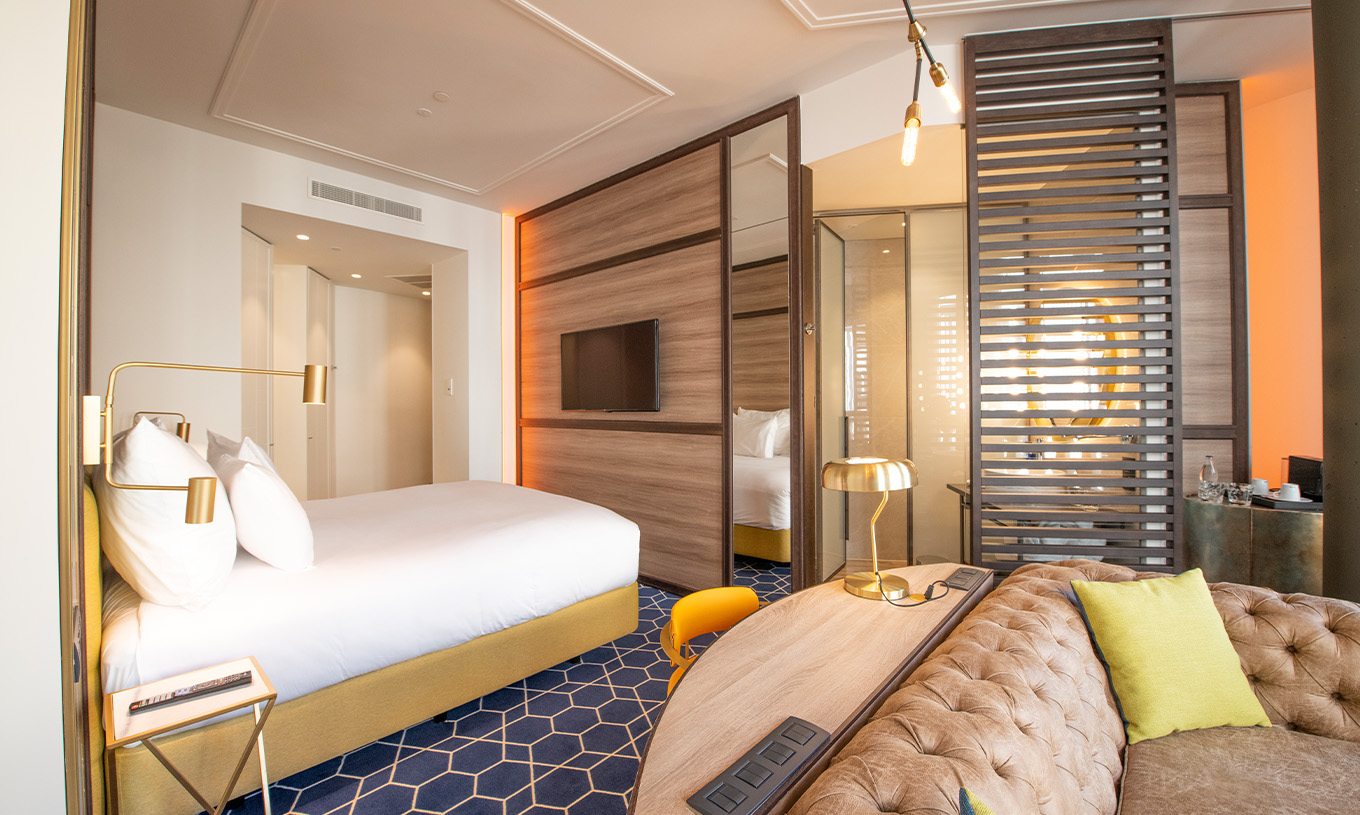 Das Fantastic 7 Zimmer im Pestana CR7 Gran Vía Madrid hat ein Doppelbett mit Sofa, Schreibtisch, Spiegel und Trennwand