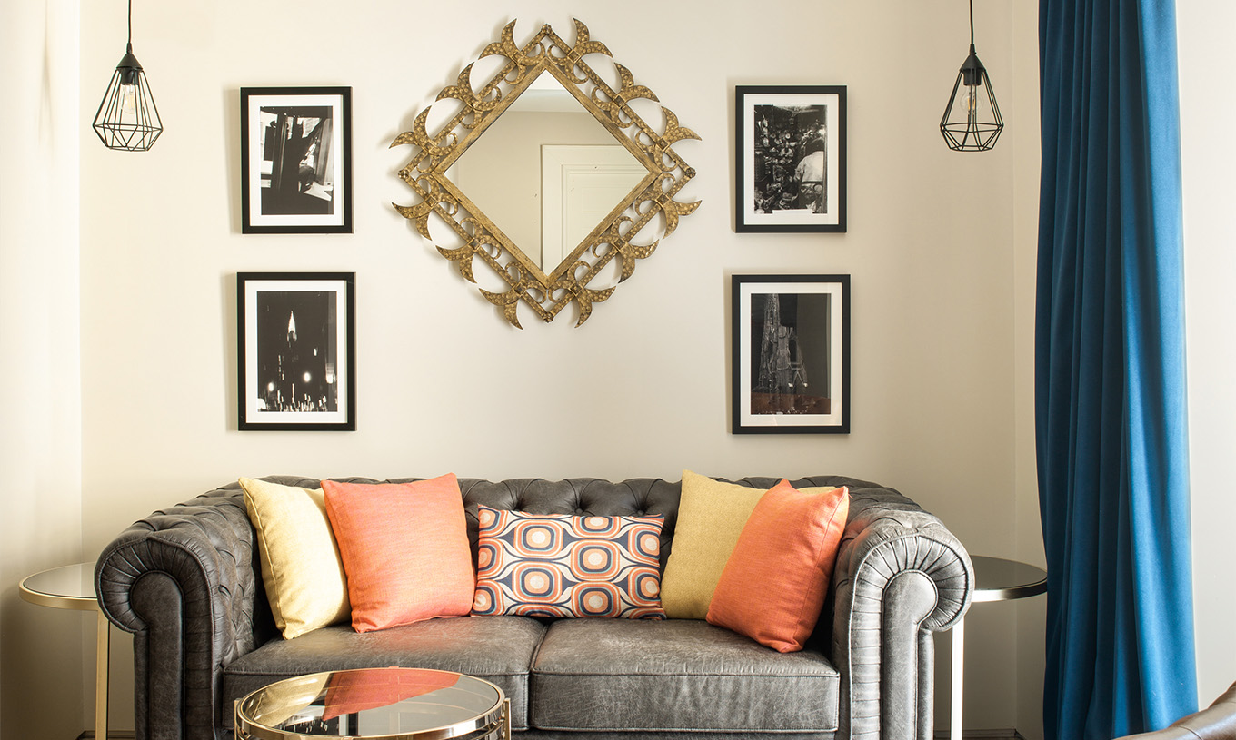 Das Deluxe Grand Plaza Mayor im Pestana Plaza Mayor Madrid hat ein graues Zweisitzer-Sofa und Bilder an der Wand