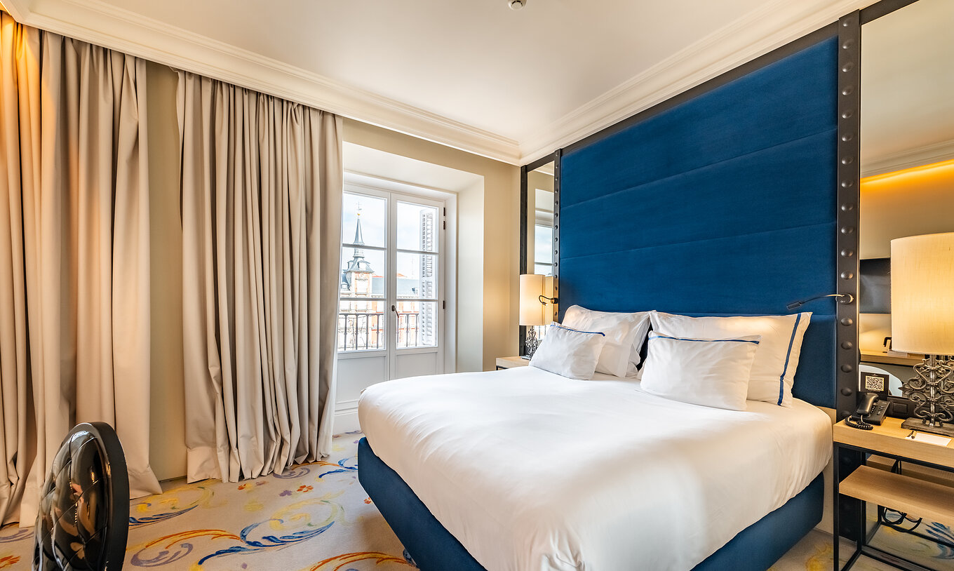 Das Deluxe Plaza Mayor im Pestana Plaza Mayor Madrid hat ein Doppelbett, zwei Nachttische und einen Spiegel an der Wand