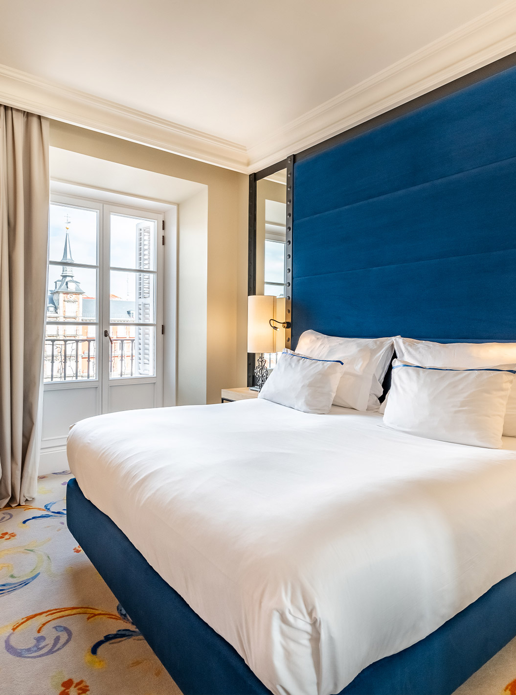 Das Deluxe Plaza Mayor im Pestana Plaza Mayor Madrid hat ein Doppelbett, zwei Nachttische und einen Spiegel an der Wand