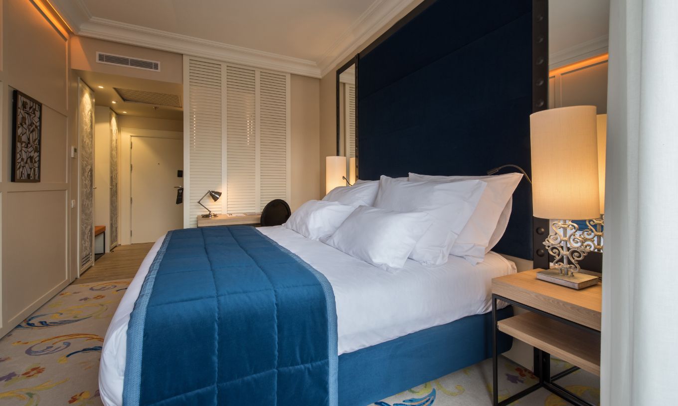 Das Superior Plus Zimmer im Pestana Plaza Mayor Madrid hat ein Doppelbett mit einer blauen Tagesdecke und einem Teppich.