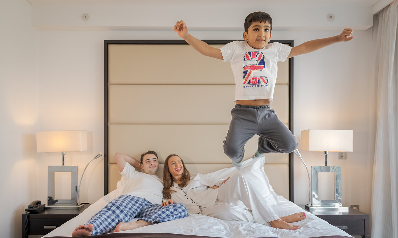 Das Deluxe Family im Pestana Chelsea Bridge hat ein Doppelbett mit liegender Familie und springendem Kind