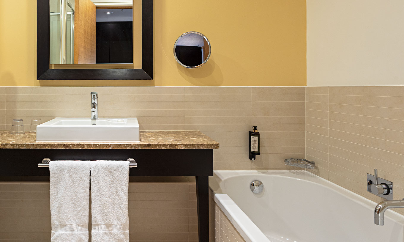 Grand-Deluxe-Zimmer im Pestana Chelsea Bridge mit Badezimmer, Badewanne, Waschbecken und großem Spiegel
