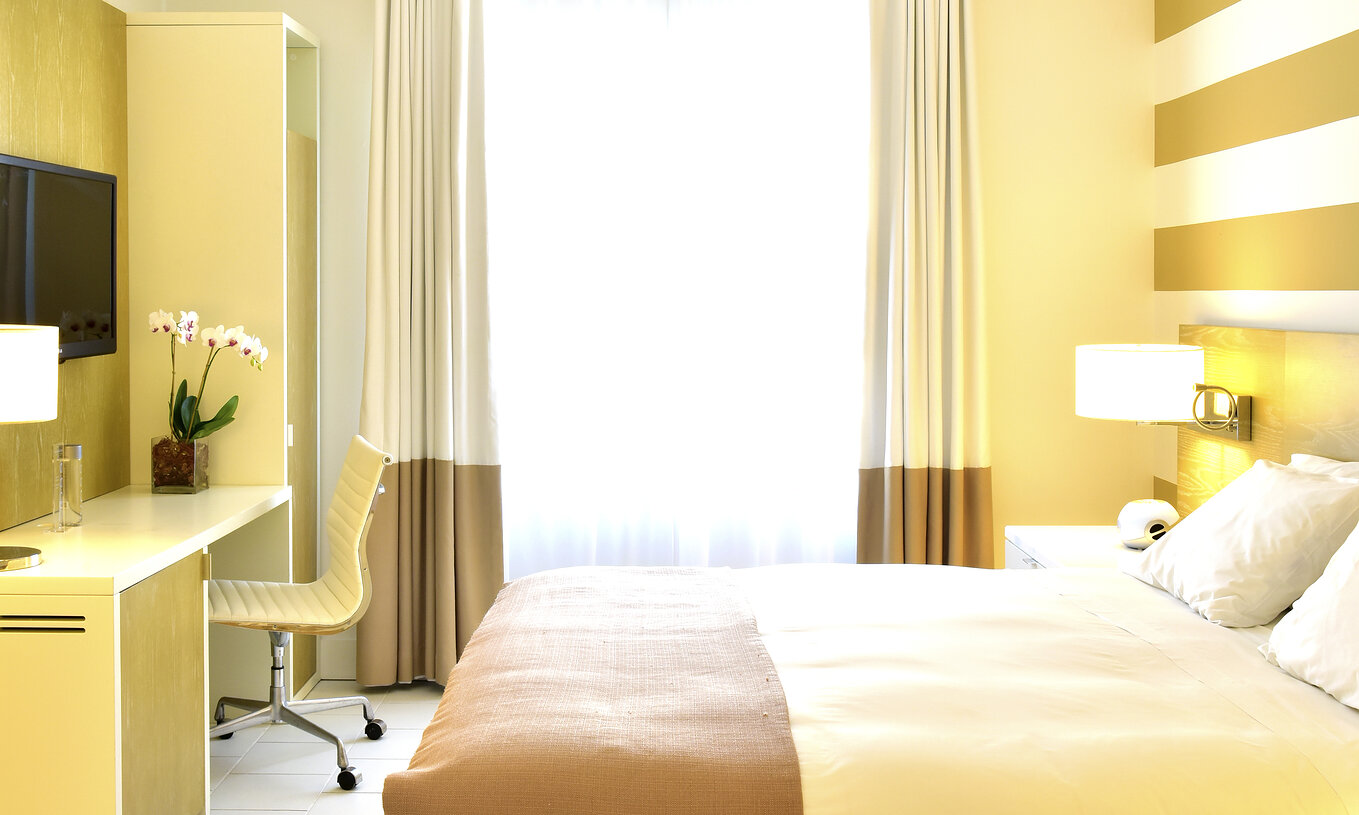 Das Art Deco King Zimmer im Pestana Miami South Beach hat Doppelbett, Nachttisch und kleinen Kleiderschrank