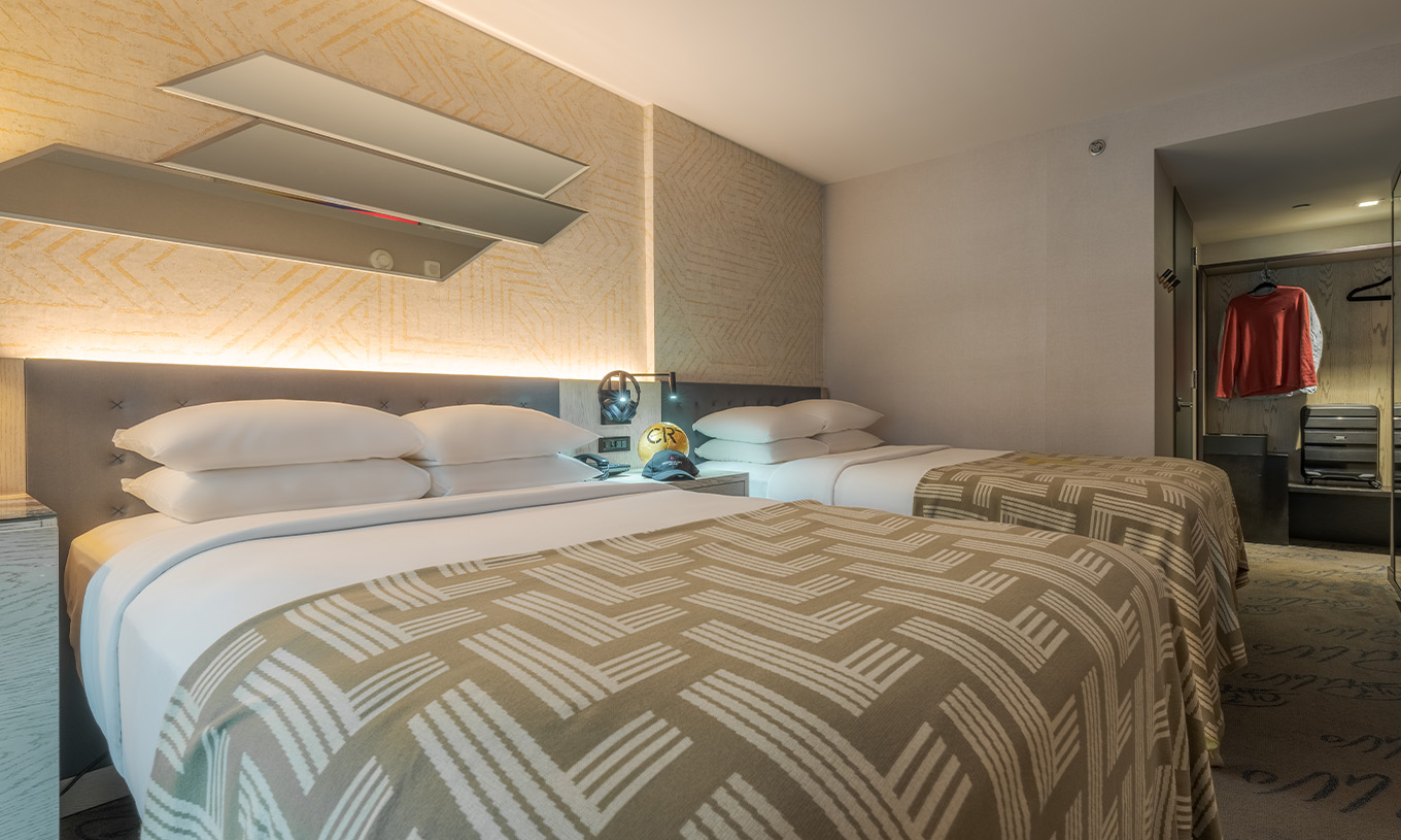 Der Comfort Double ADA im Pestana CR7 Times Square hat zwei Betten mit einer Decke mit der Zahl sieben und einem Schrank