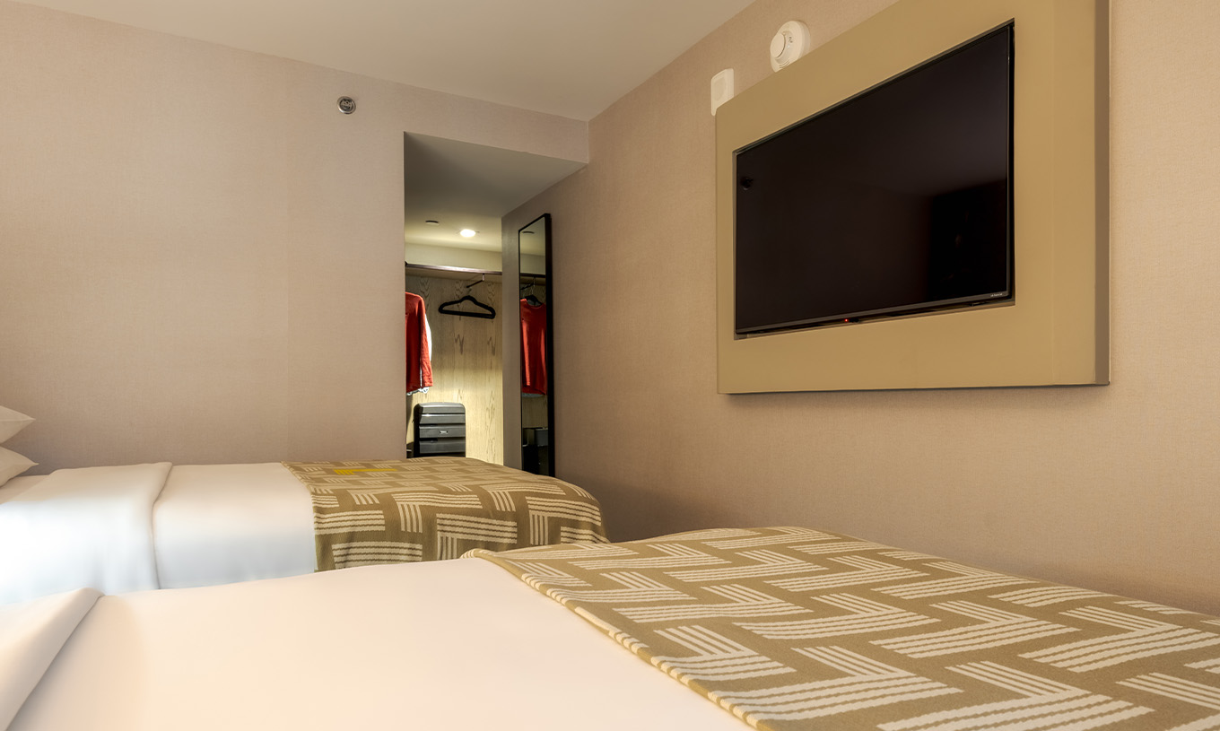 Der Comfort Double ADA im Pestana CR7 Times Square hat zwei Betten mit einer Decke mit der Zahl sieben und einem Fernseher