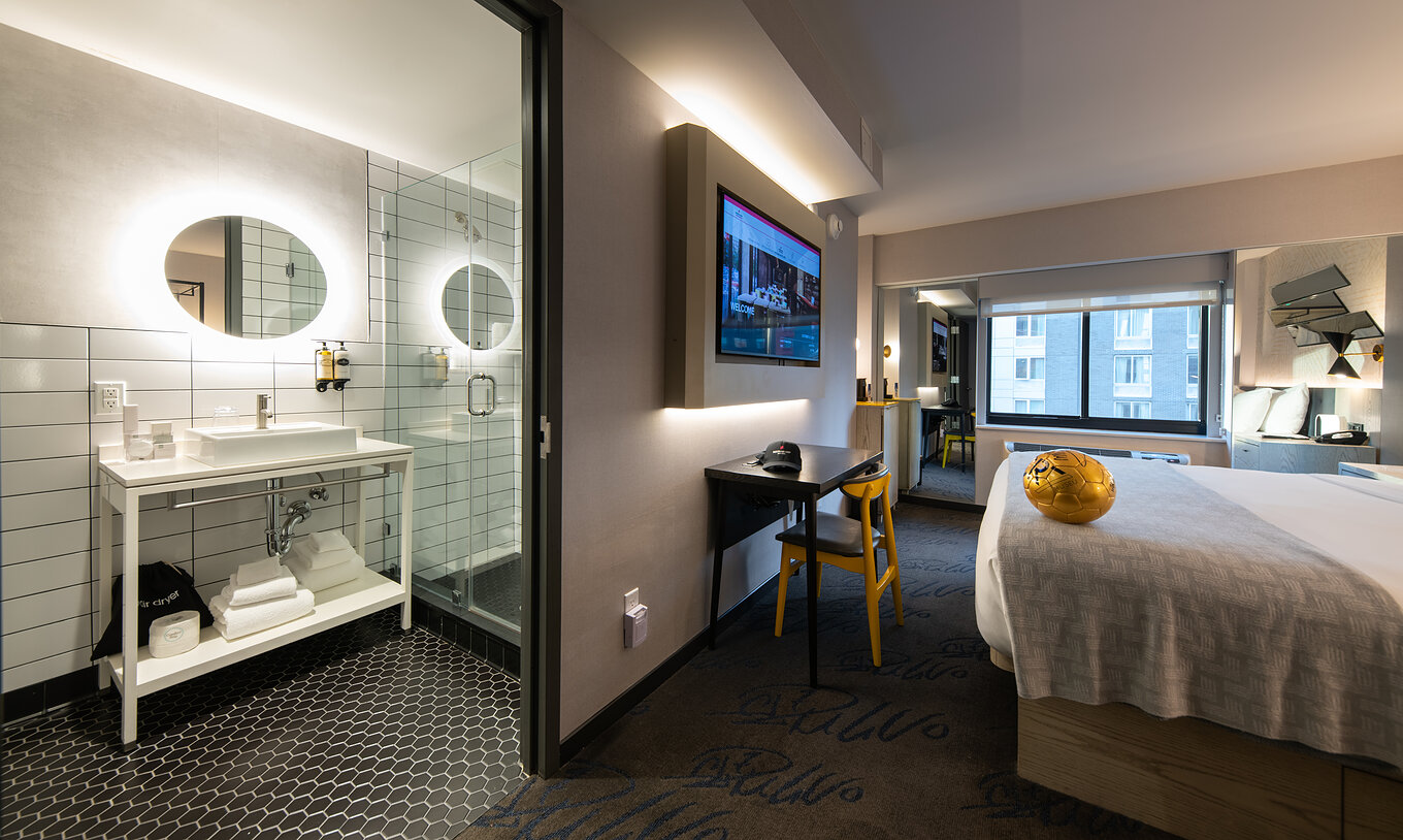 Das Deluxe King Room im Pestana CR7 Times Square hat ein Badezimmer neben dem Zimmer mit einem Waschbecken