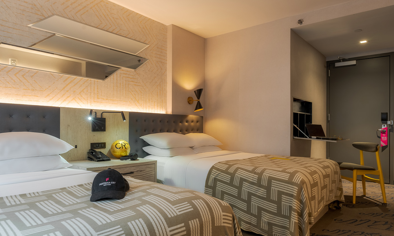 Der Superior Double ADA im Pestana CR7 Times Square hat zwei Betten mit einer Decke mit der Zahl sieben und einem Tisch