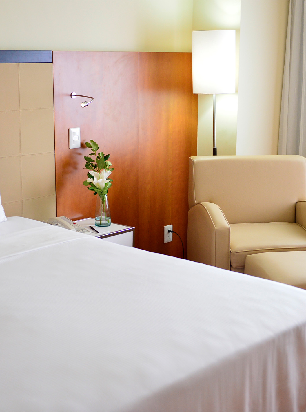 Der Twin Executive im Pestana Caracas hat ein Doppelbett, eine Blume auf dem Nachttisch und einen beigen Sessel