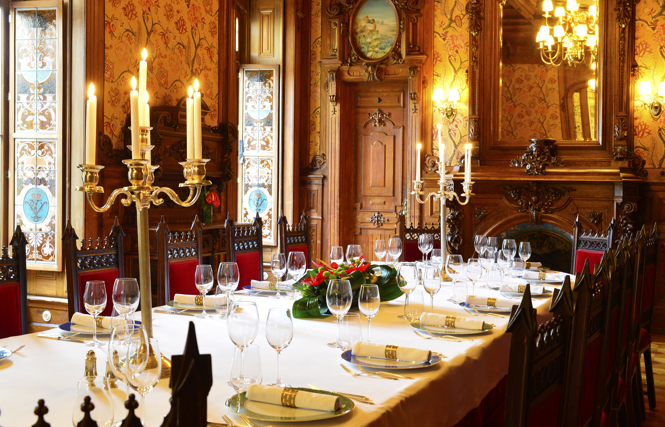 Hochzeit in einem imposanten Raum mit eleganter Deko, langer Tafel, Blumengestecken und geschnitzten Holztafeln