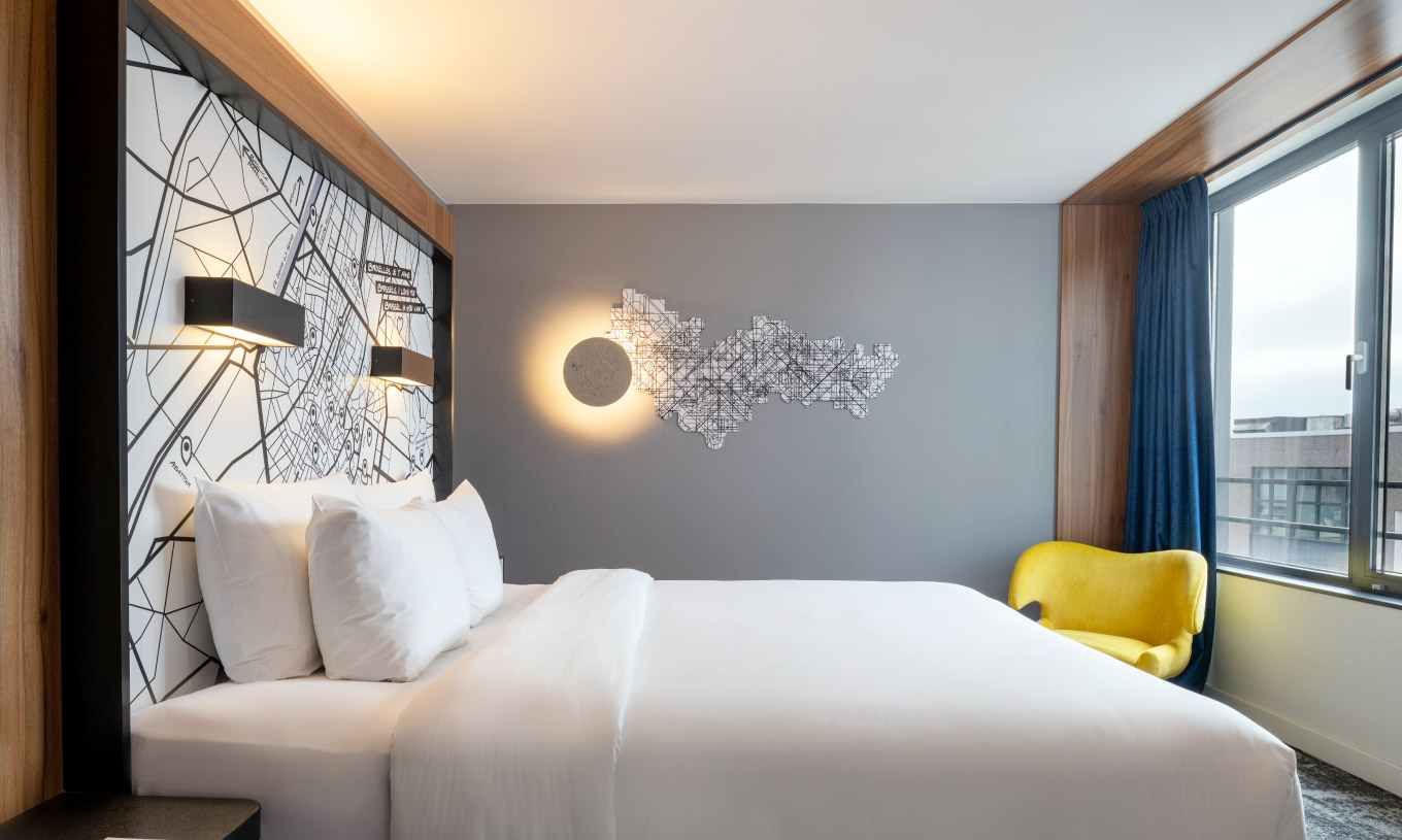 The Superior King at Pestana Brussels Schuman has a double bed with white sheets and a wall lamp