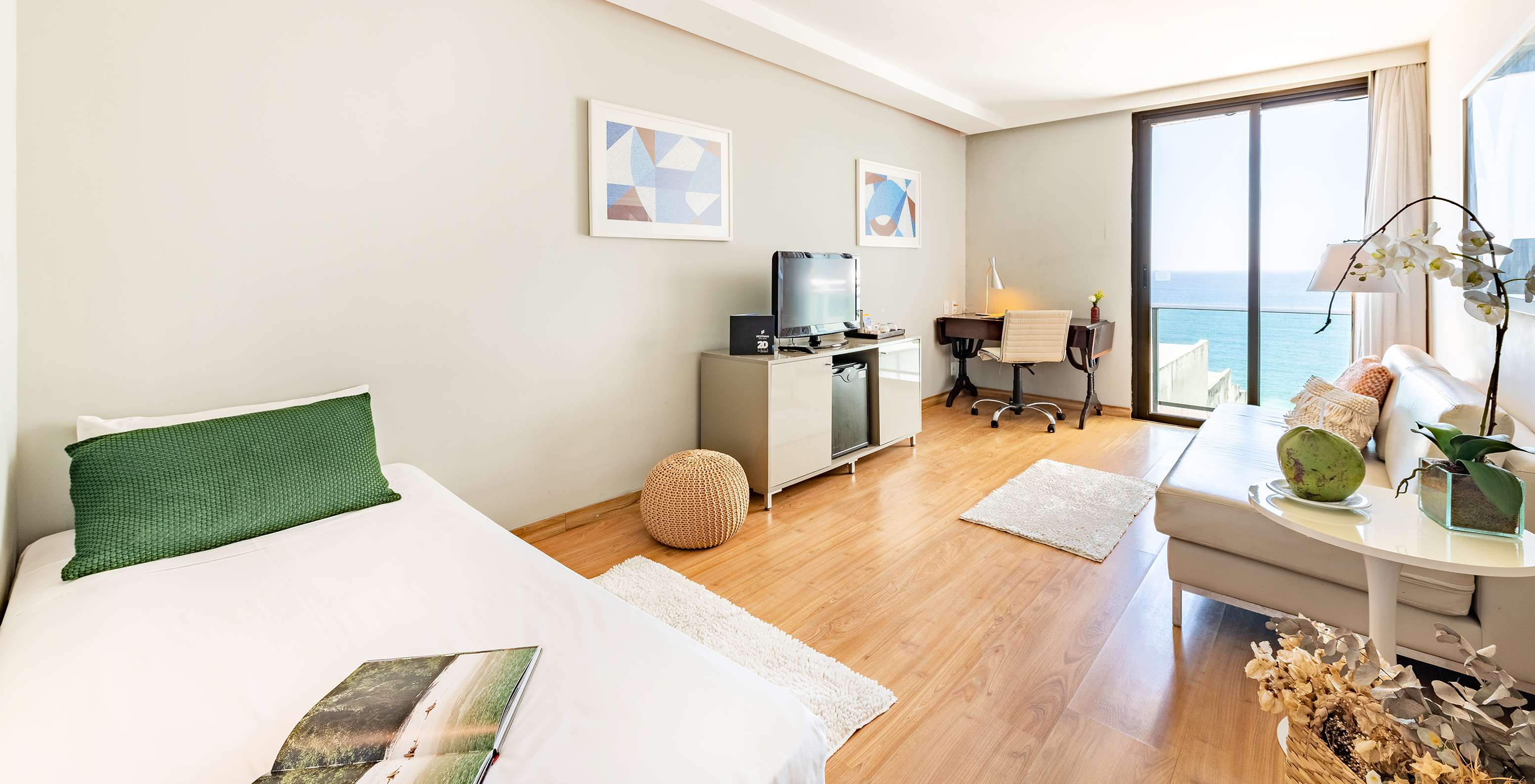 The Suite Side Sea View of Pestana Rio Atlântica has a living room with a sofa, television, and window with sea view