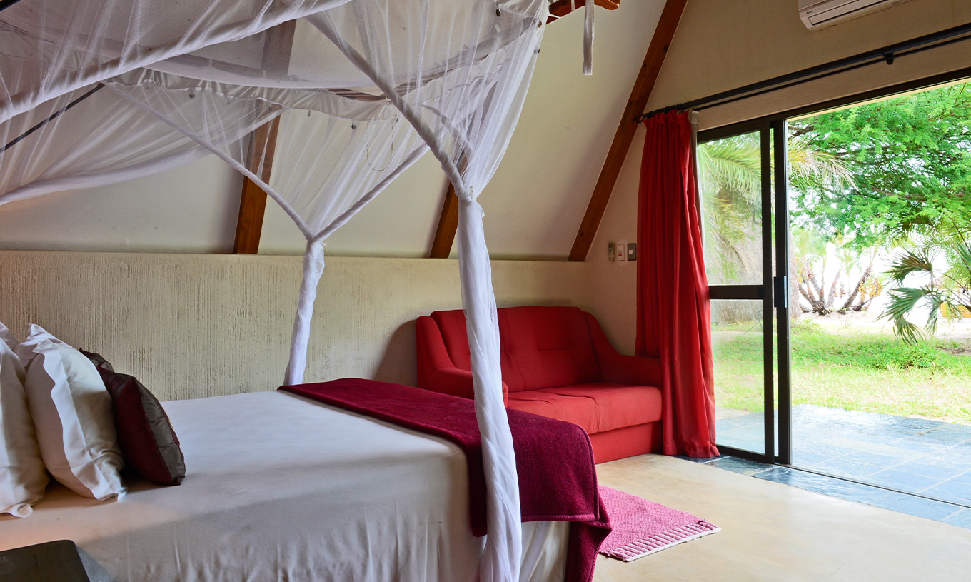 Bungalow Suite T2 at Pestana Bazaruto Lodge has a bed with canopy and garden view and a double sofa on the side