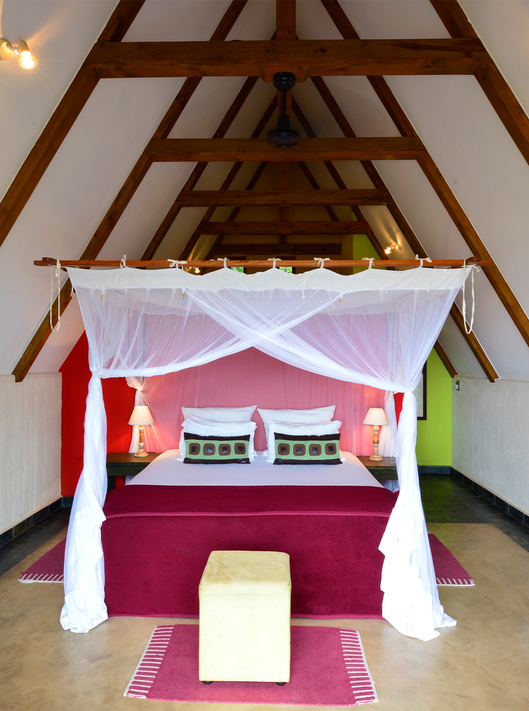 Bungalow T1 at Pestana Bazaruto Lodge has a double bed with canopy, a sofa and a desk with a bowl of fruit