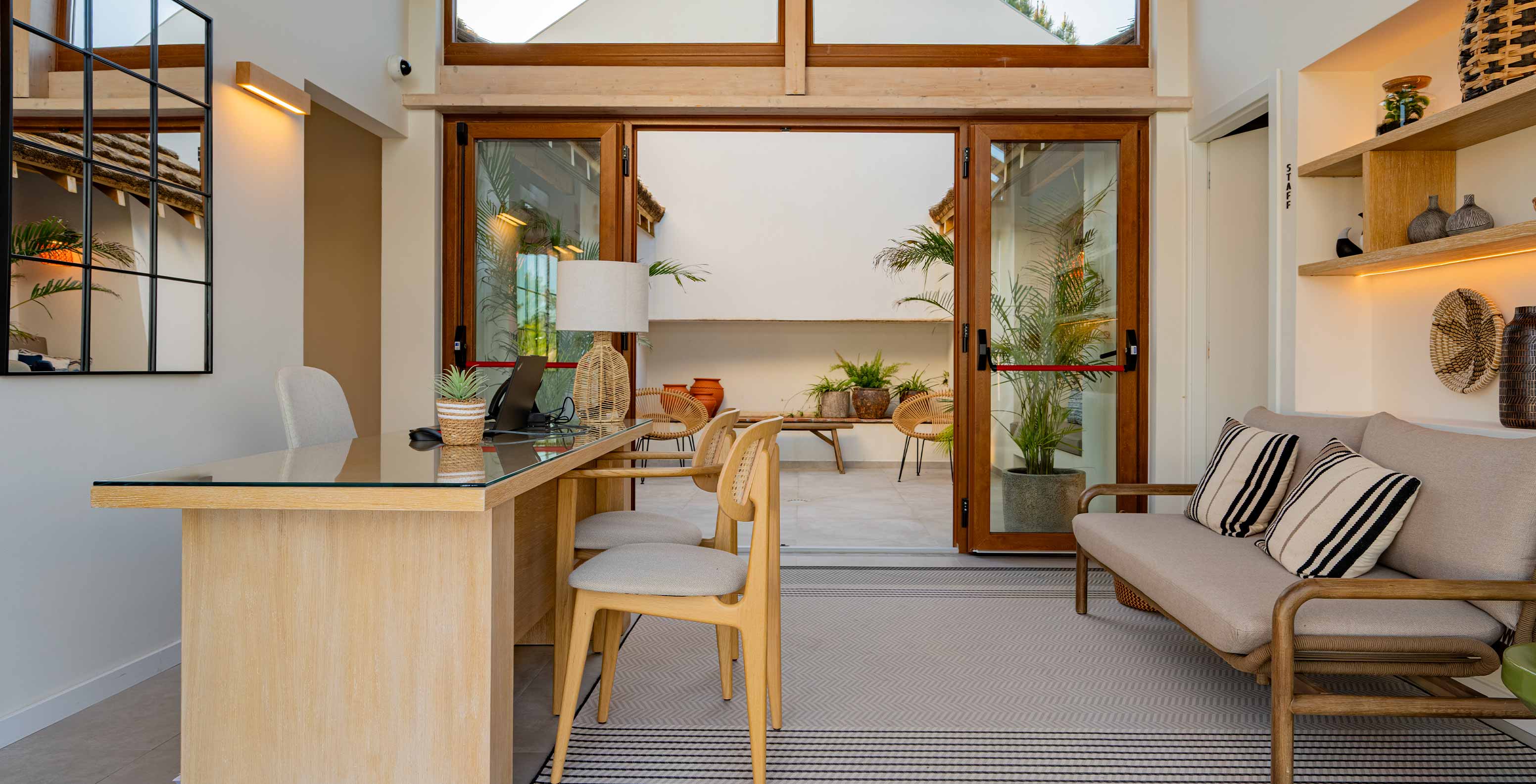 Modern and cozy reception area with a sofa and double glass doors, at Pestana Comporta Village Residences