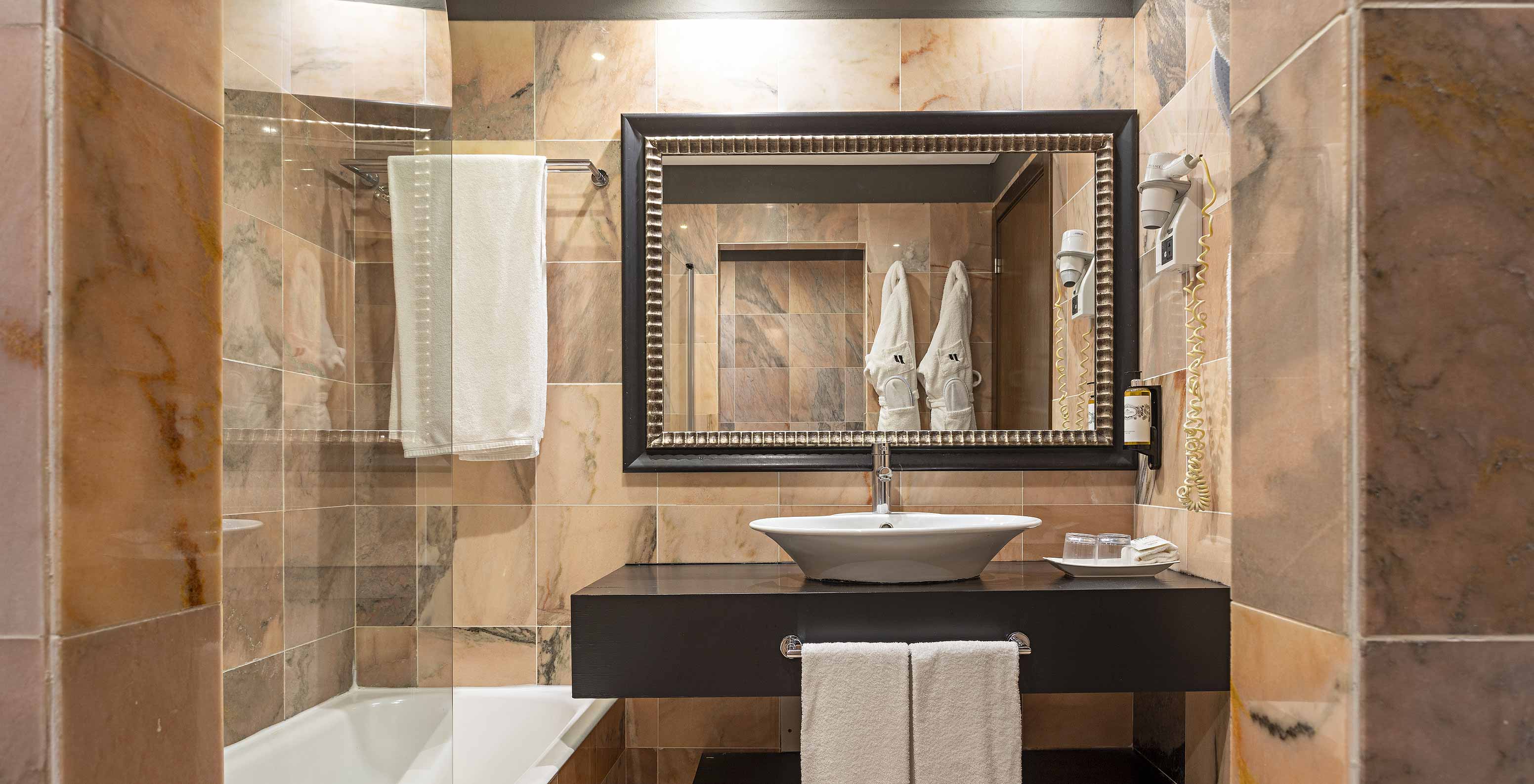 The Cliff Studio at Pestana Alvor Praia has a bathroom with a bathtub, two bathrobes, and a hairdryer