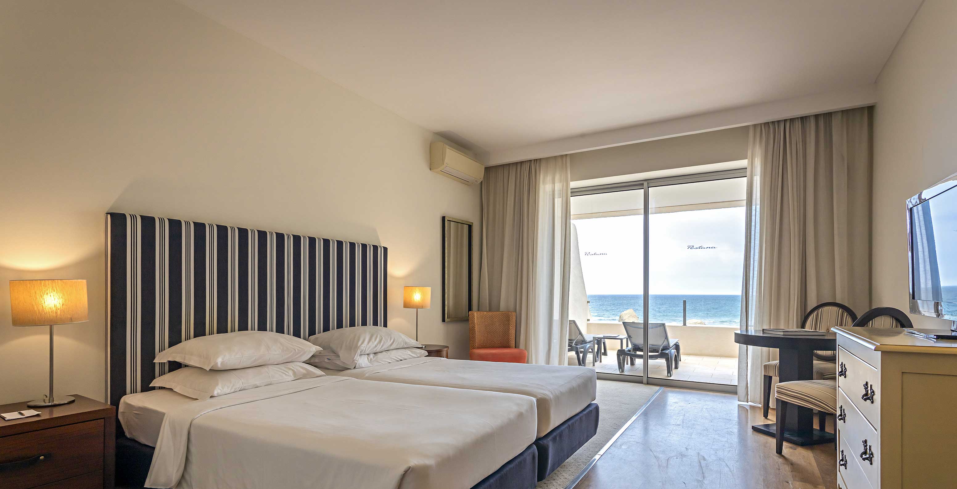 The Cliff Suite T1 at Pestana Alvor Praia has a double bedroom with a balcony with sun loungers and a sea view