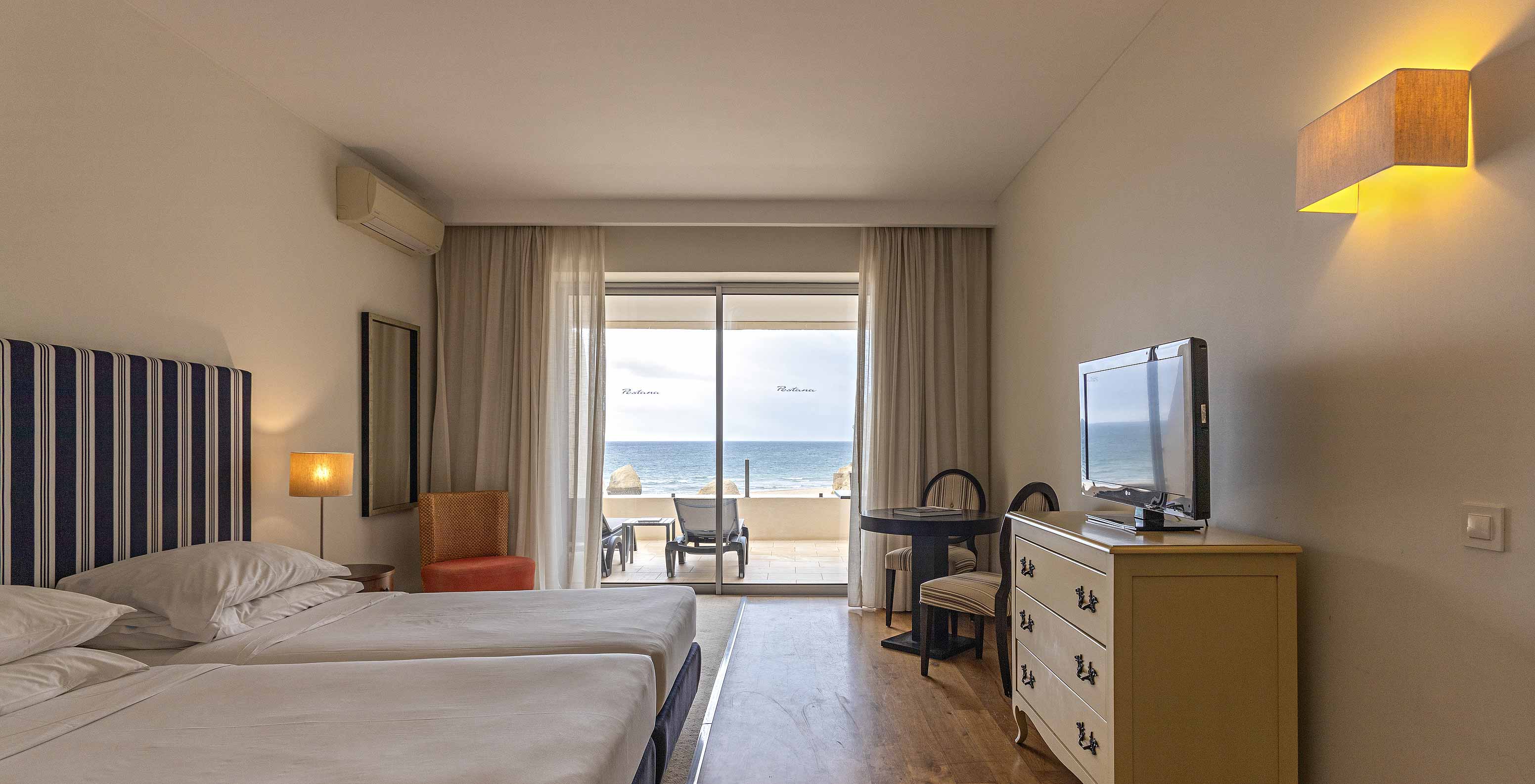The Cliff Suite T1 at Pestana Alvor Praia has a double bedroom with a dresser, a television, and a balcony with a view