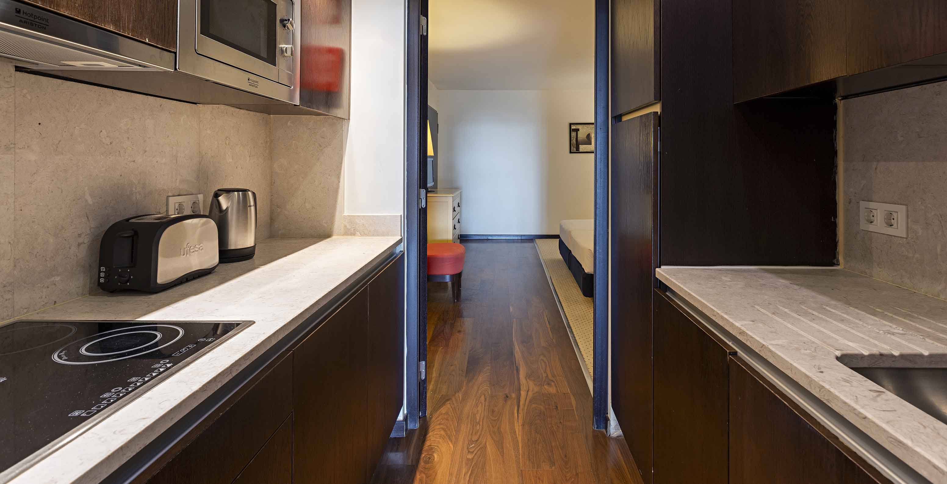 The Cliff Suite T2 at Pestana Alvor Praia has a fully equipped kitchen in dark wood and stone, with a stove and a microwave