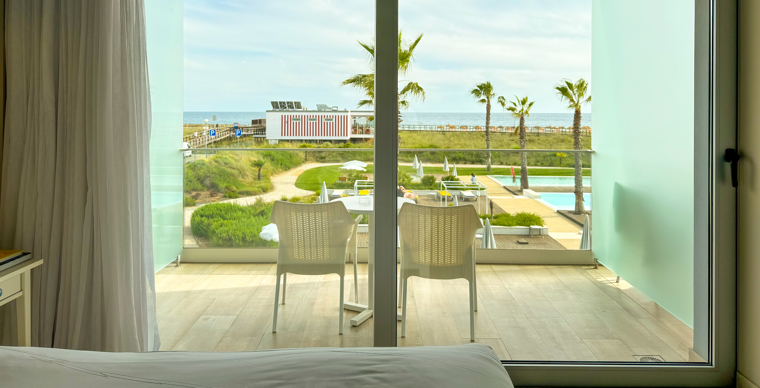 The Deluxe Sea View of Pestana Alvor South Beach has a balcony with table and chairs and view of the pool and beach