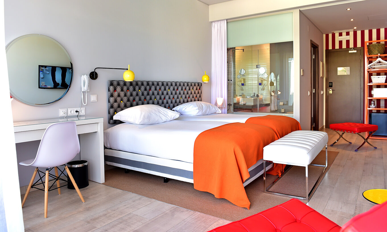 The Deluxe Pool View of Pestana Alvor South Beach has two single beds together and a stool at the foot of the bed