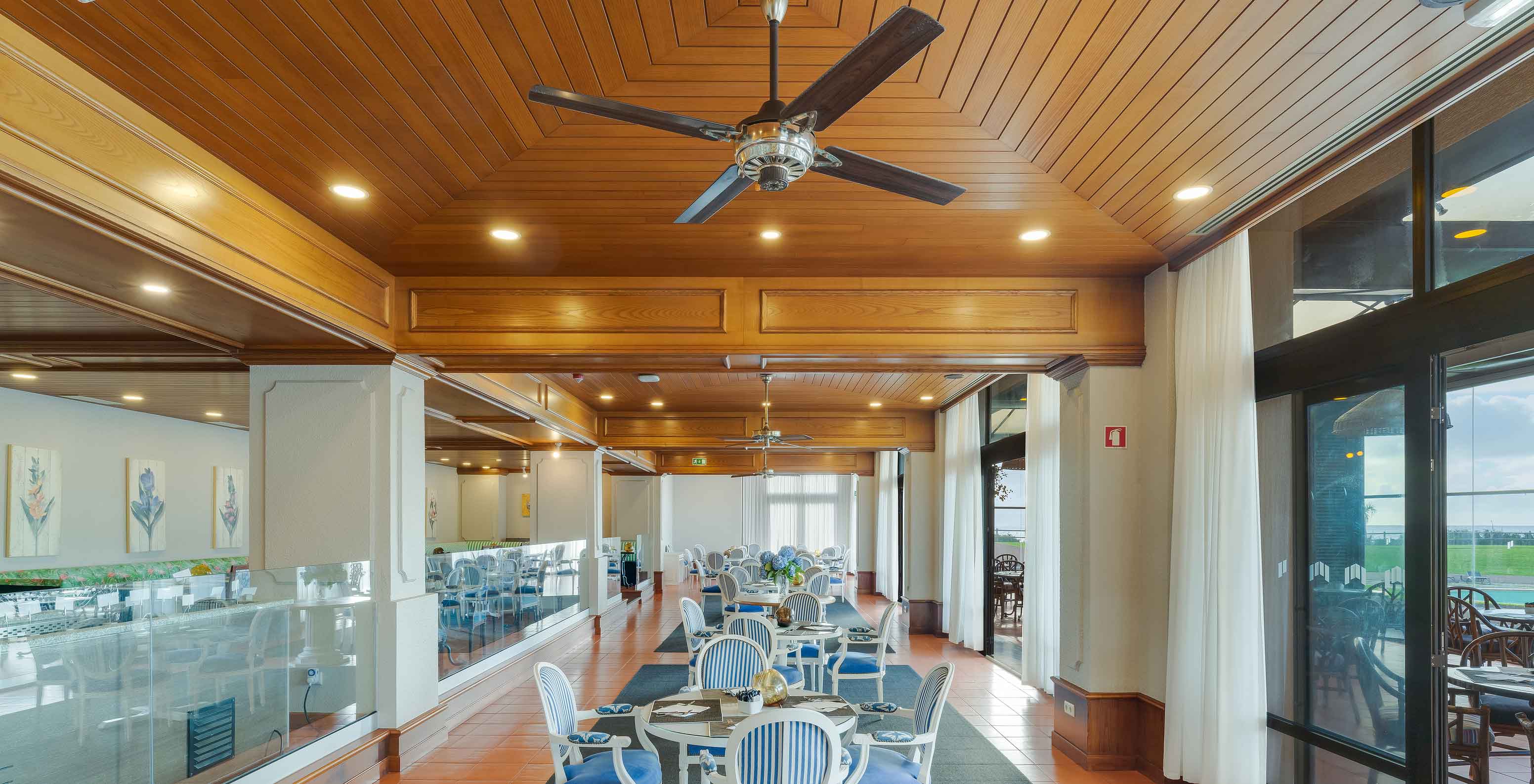 Lugar da Praia restaurant at Pestana Bahia Praia with tables, chairs, wooden ceiling, and large windows with view