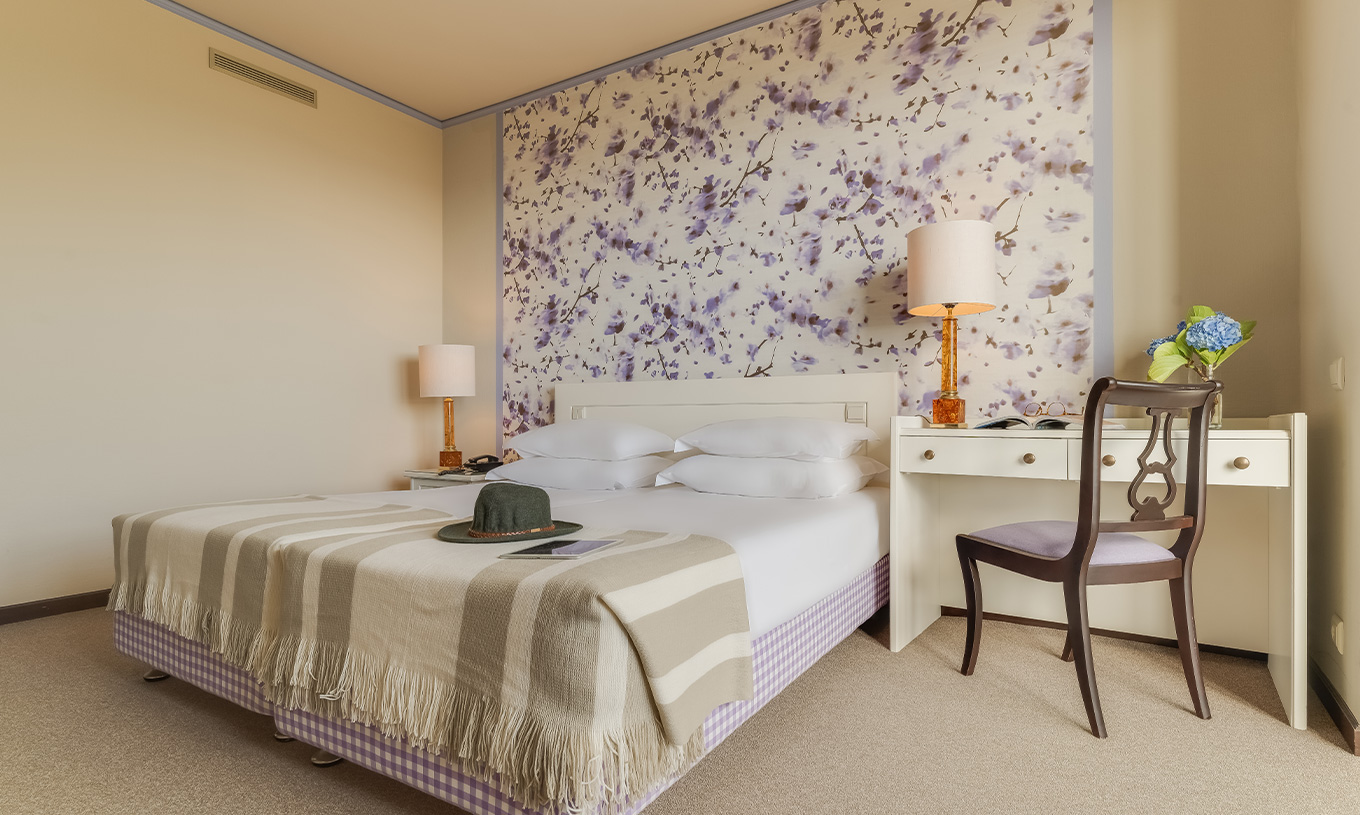 Standard Garden View room at Pestana Bahia Praia has a bed with 4 pillows and a desk beside the bed with a chair