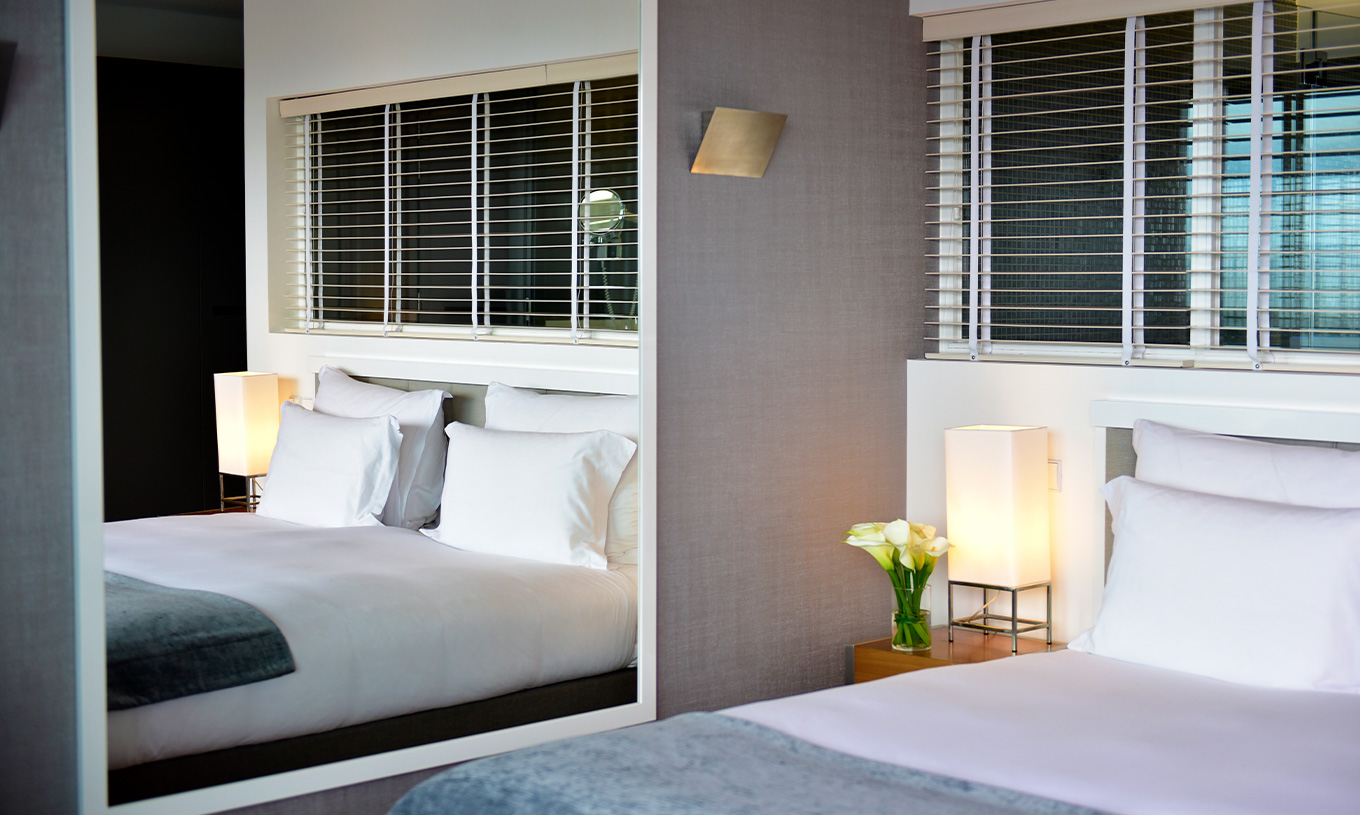 The Sea View Suite at Pestana Cidadela Cascais has a double bed, a bedside table, and a large mirror