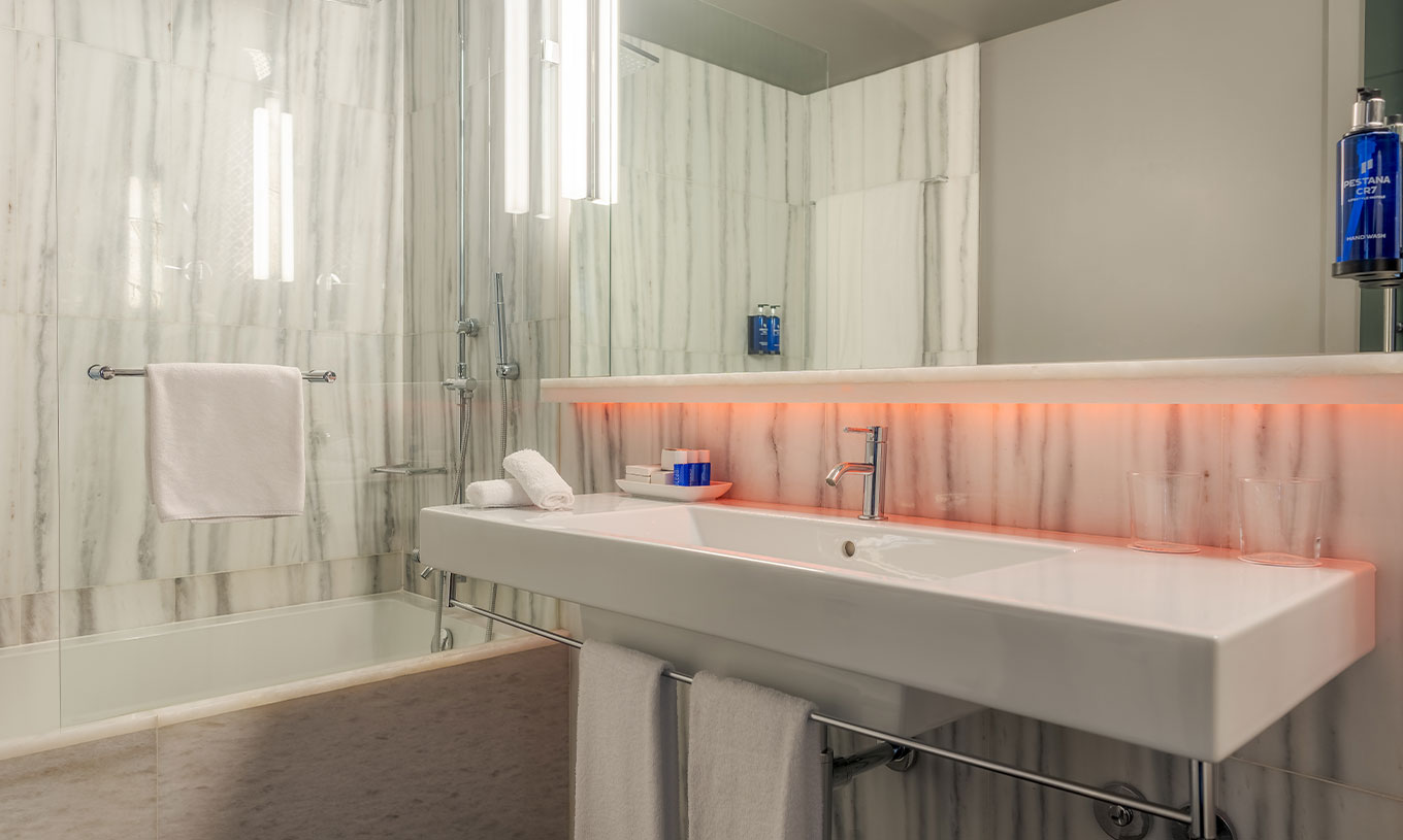 The CR7 Superior Corner Room at Pestana CR7 Lisboa features a bathroom with mirror, sink, and bathtub with shower