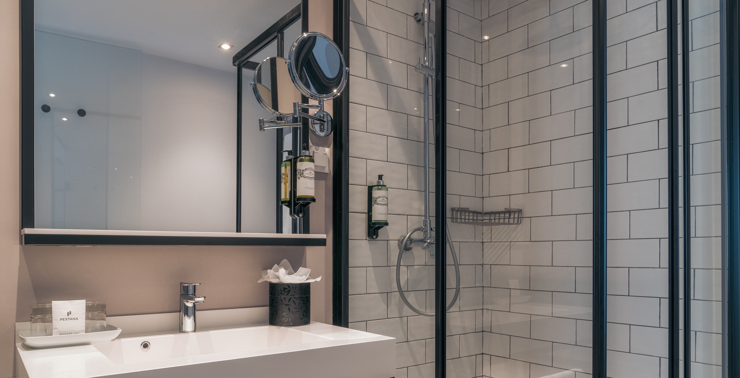The Vintage Room at Pestana Lisboa Vintage has a shower with glass doors and black details and a sink with two mirrors