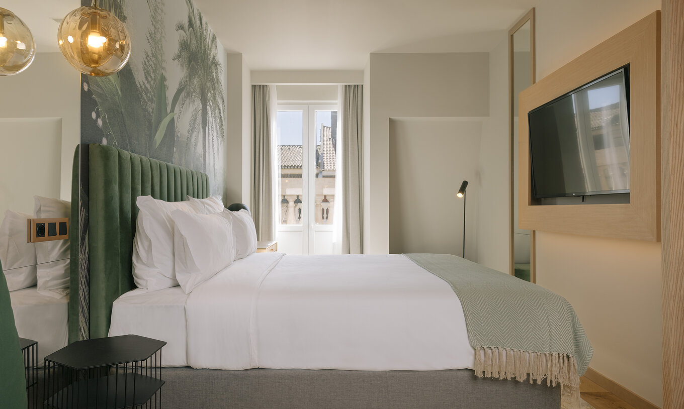 The Superior Plus of Pestana Rua Augusta Lisboa has a double bed, palm wallpaper, and a window with curtains